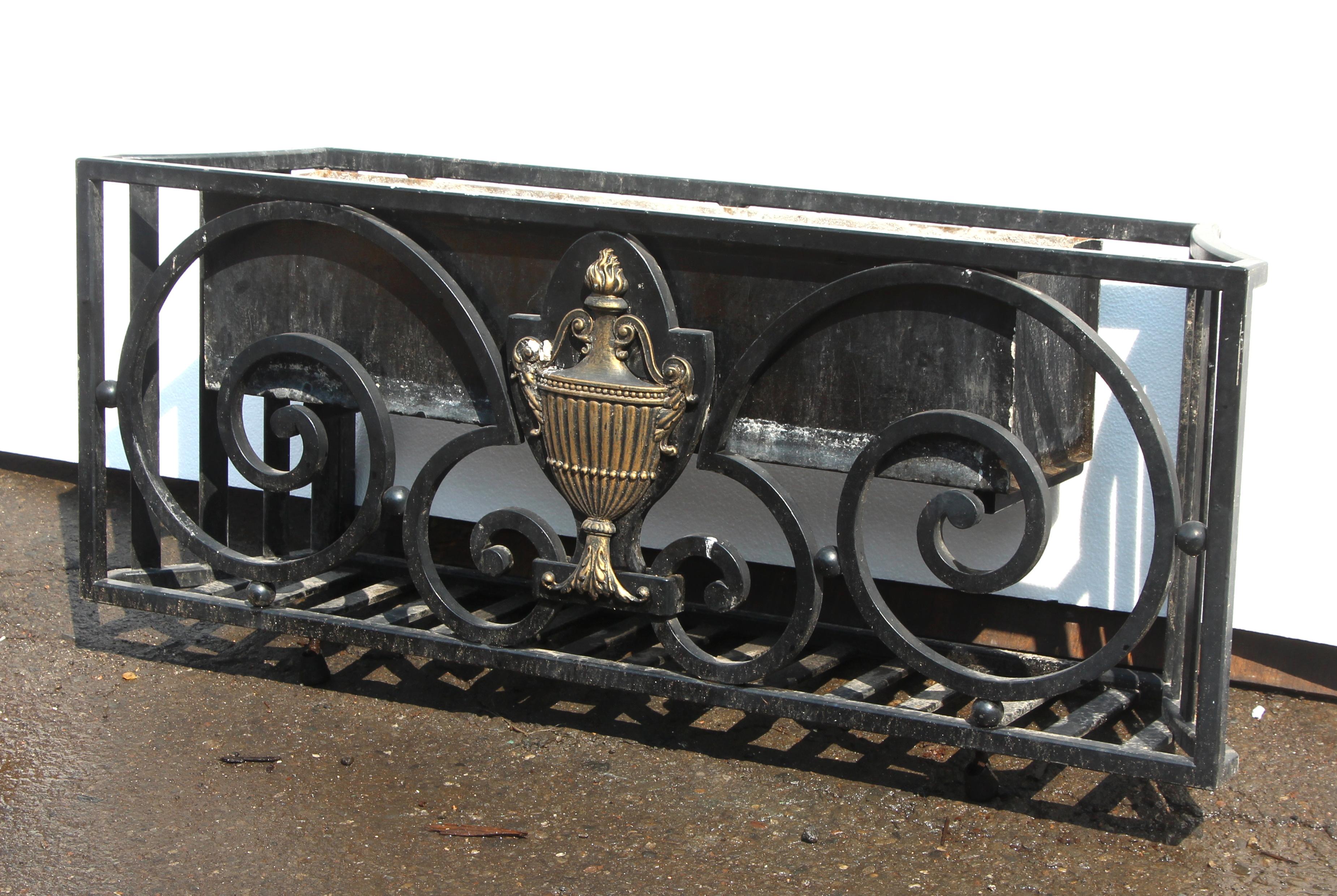 Early 20th century wrought iron window garden box with scrolling wrought iron and brass Georgian urn with flame finial center motif. Four available at time of listing. These are in good condition, ready to install. Small quantity available at time