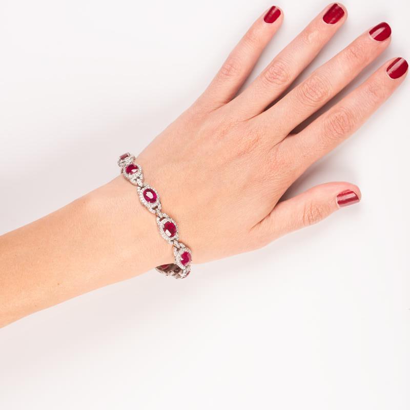 This exquisite bracelet features 19.21ct total weight in oval shaped, intensely red rubies surrounded by 4.48ct total weight in round pave diamonds, linked together. These stones are all set in a 14kt white gold 7.5 inch bracelet.