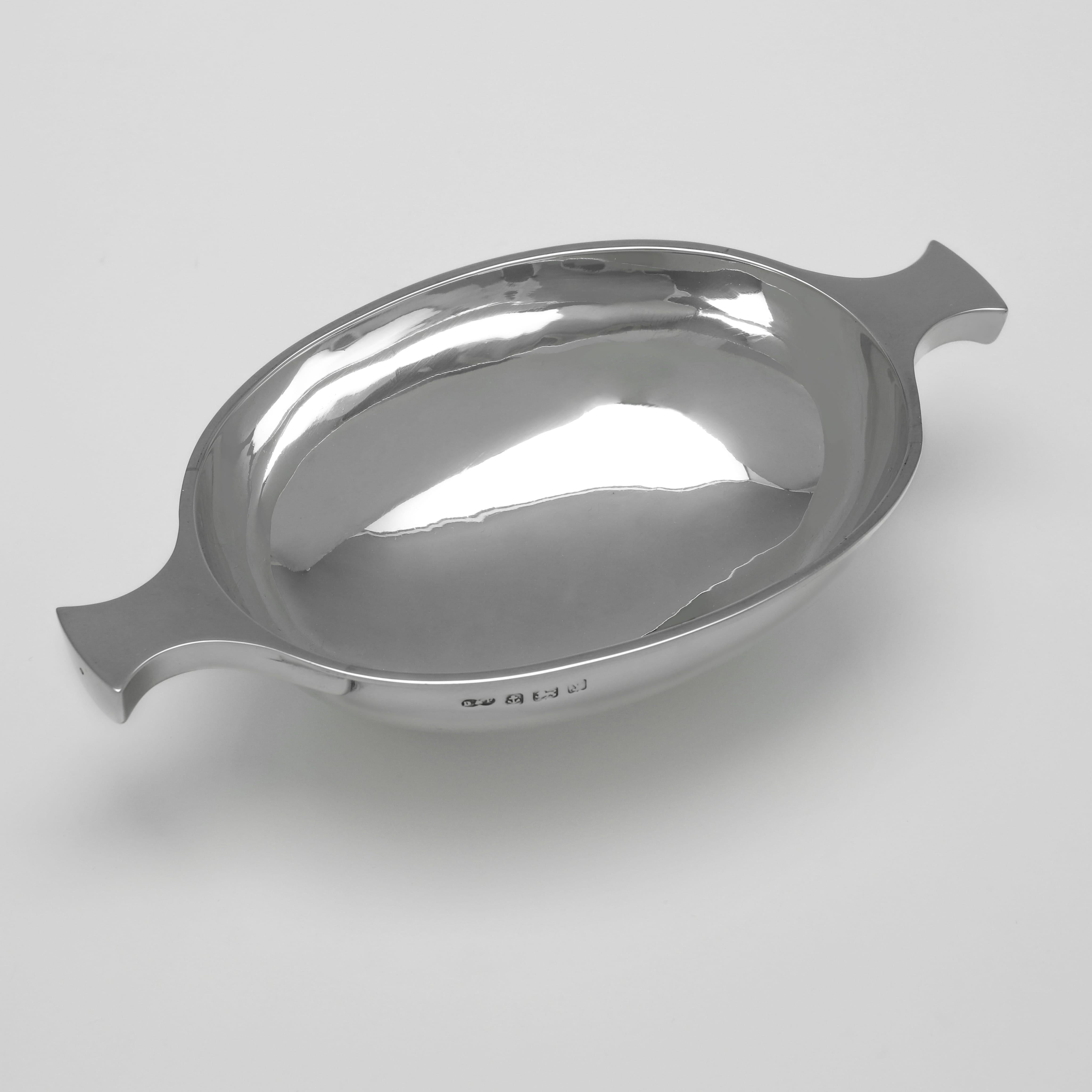 Hallmarked in Birmingham in 1923 by Deakin 
Francis, this handsome antique sterling silver quaich is of oval form, with twin side handles and a plain polished finish. Set on a collet foot, it measures 1.5