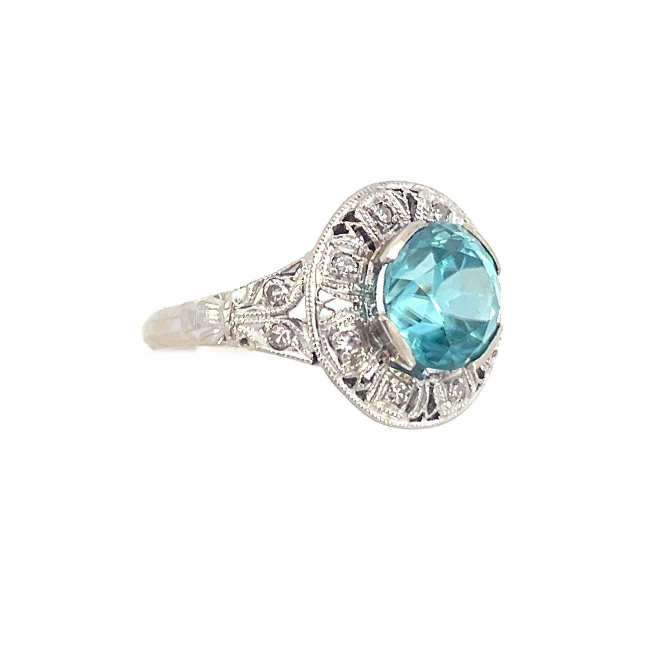 This is an alluring Art Deco ring crafted in 14K white gold showcasing a breathtaking 3-carat blue Zircon surrounded by sparkling diamonds. Looking into the 3.00-carat zircon in this eye-catching Art Deco ring is like gazing into a blue ocean that