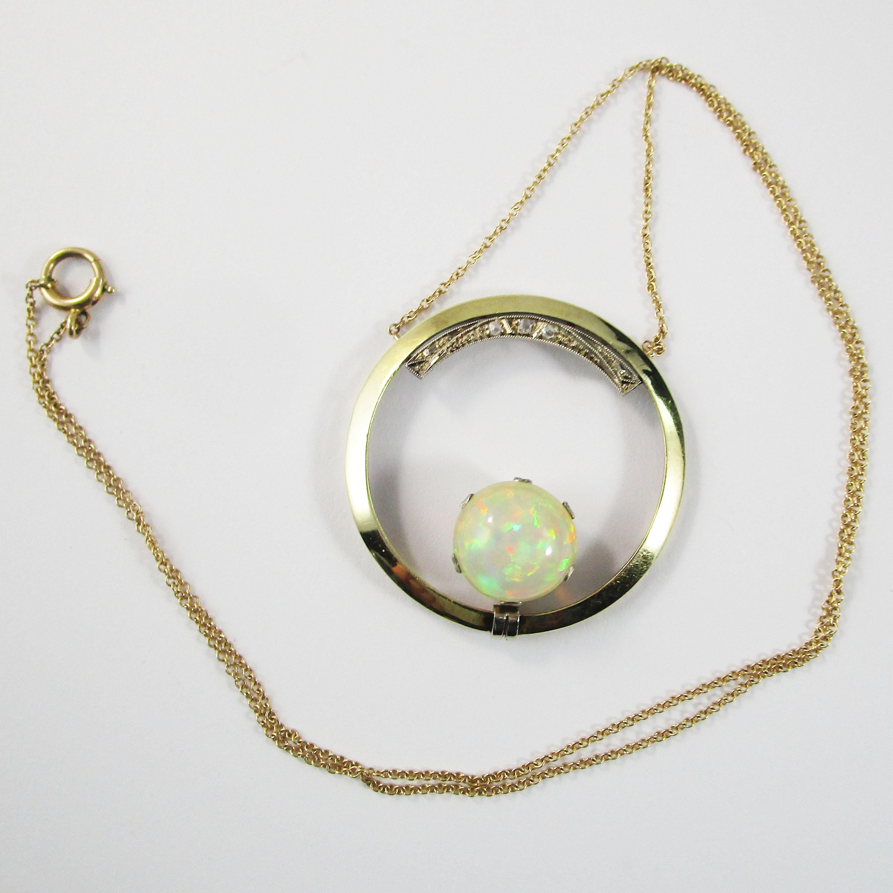 This is a stunning Art Deco necklace in 14k yellow gold with an open circle design accented by diamonds and a breathtaking opal center! The center of the necklace is an open circle in 14k yellow gold. The top of the circle is decorated with delicate