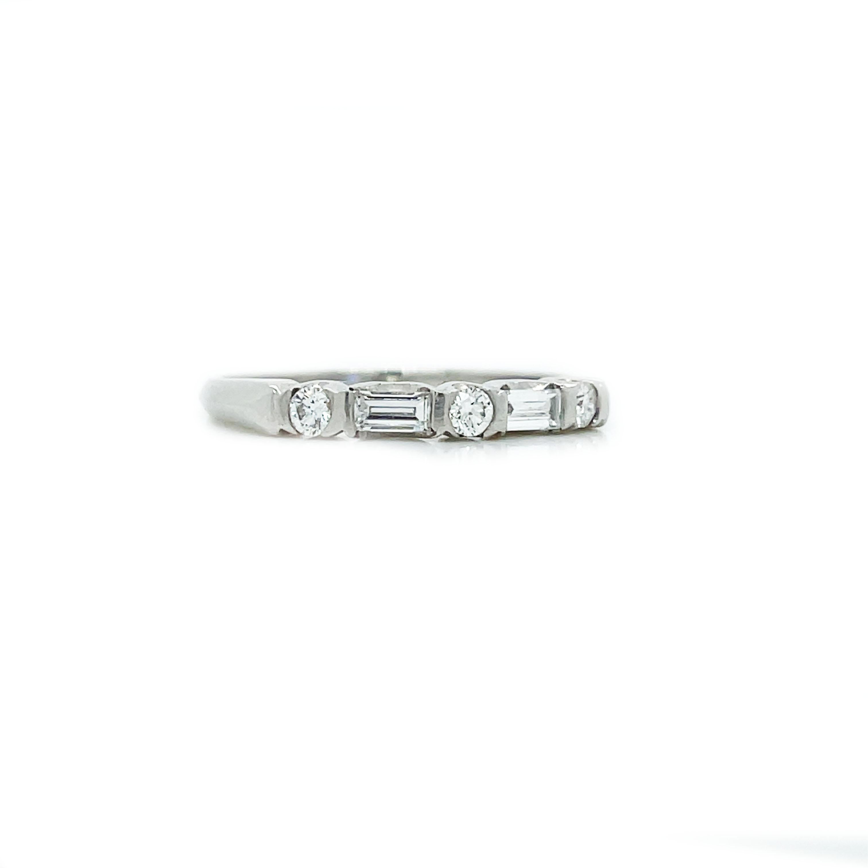 This is an elegant 1925 Art Deco platinum band showcasing a gleaming combination of round and baguette cut diamonds! This classic platinum ring is sleek and refined, alternately sparkling and gleaming with bright-white round and baguette diamonds.