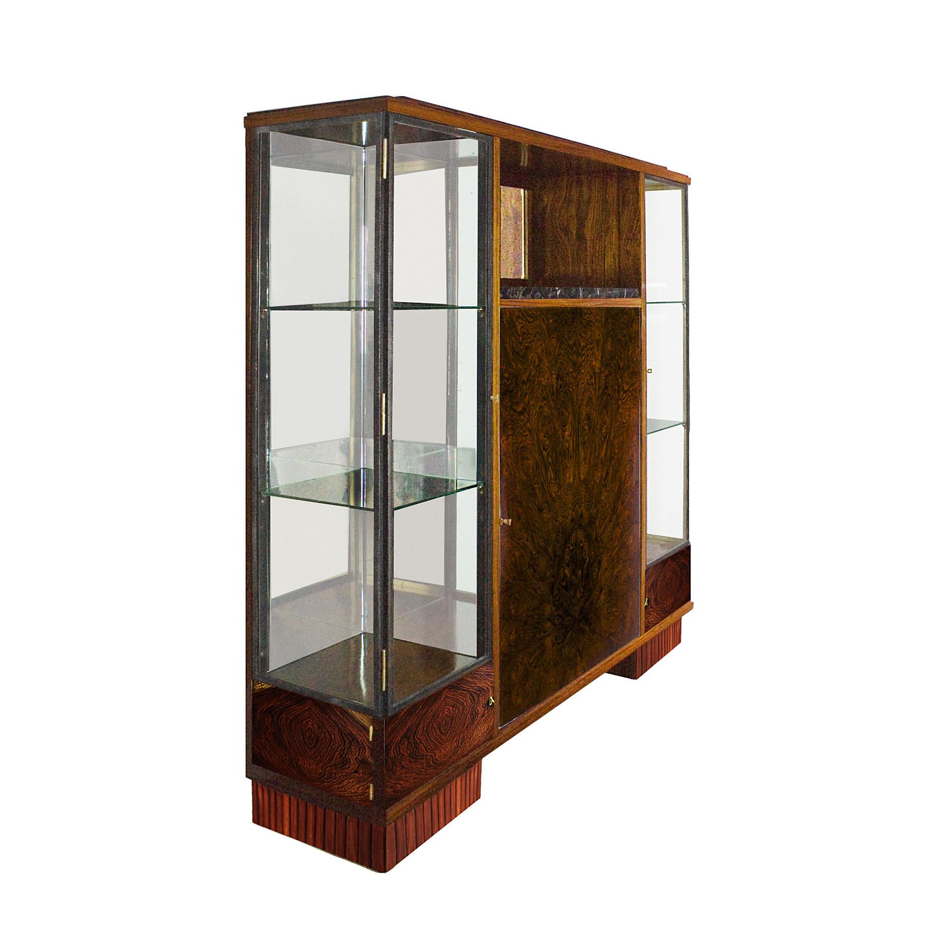 Large Art Deco cabinet-showcase, wood structure that can be completely dismantled. Central block with one door in splendid mahogany veneer and mahogany shelves and one niche with Portor marble and beveled mirror, French polish. Two large showcases