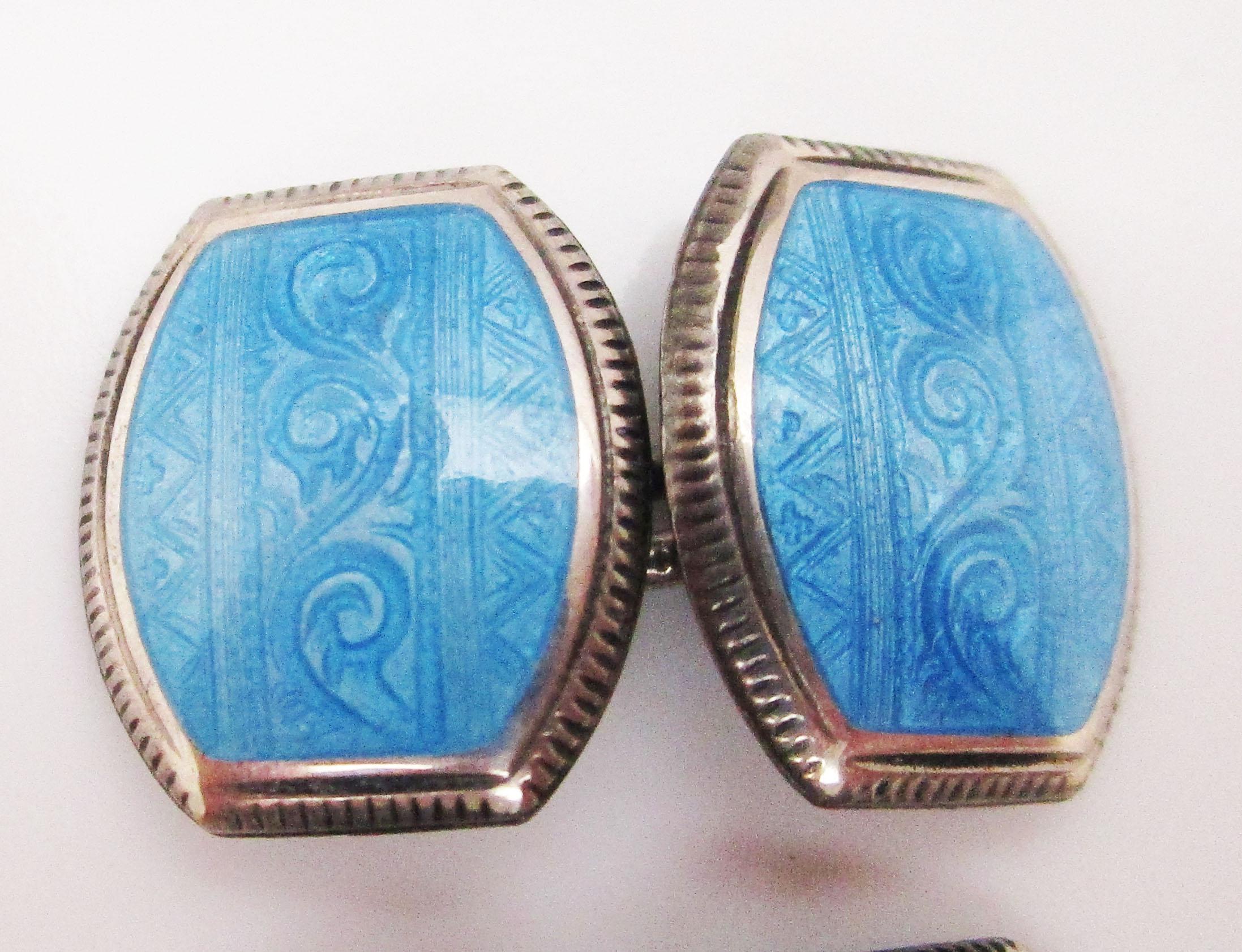 These Art Deco cufflinks are from 1925 and feature bright sterling silver and sky-blue enamel! The panels have a gorgeous swirled, geometric design in the blue enamel and are framed by engraved sterling silver. The panels have a rounded rectangle