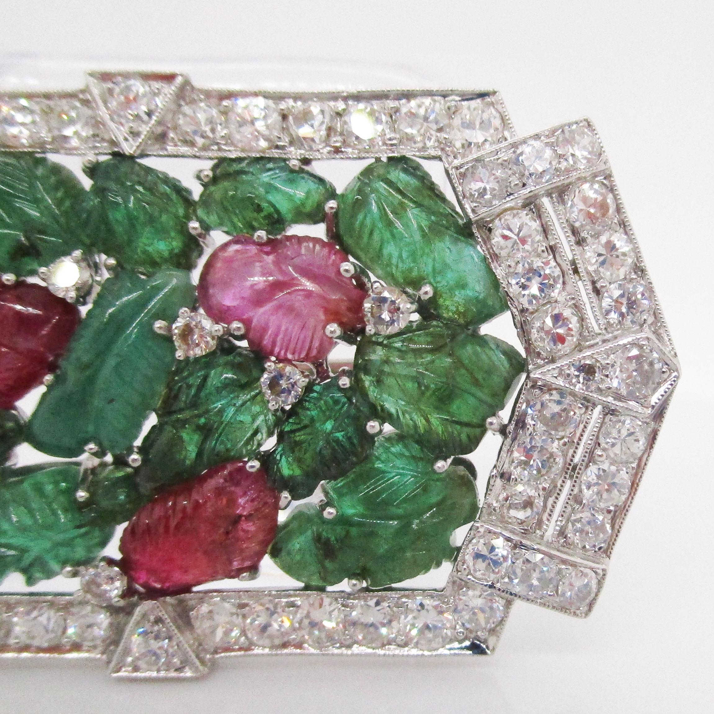 This absolutely breathtaking platinum brooch is a tour de force Art Deco piece, dating back to 1925 and featuring an enthralling combination of carved emeralds and rubies within a diamond frame in the envied Tutti Frutti style! The emeralds and