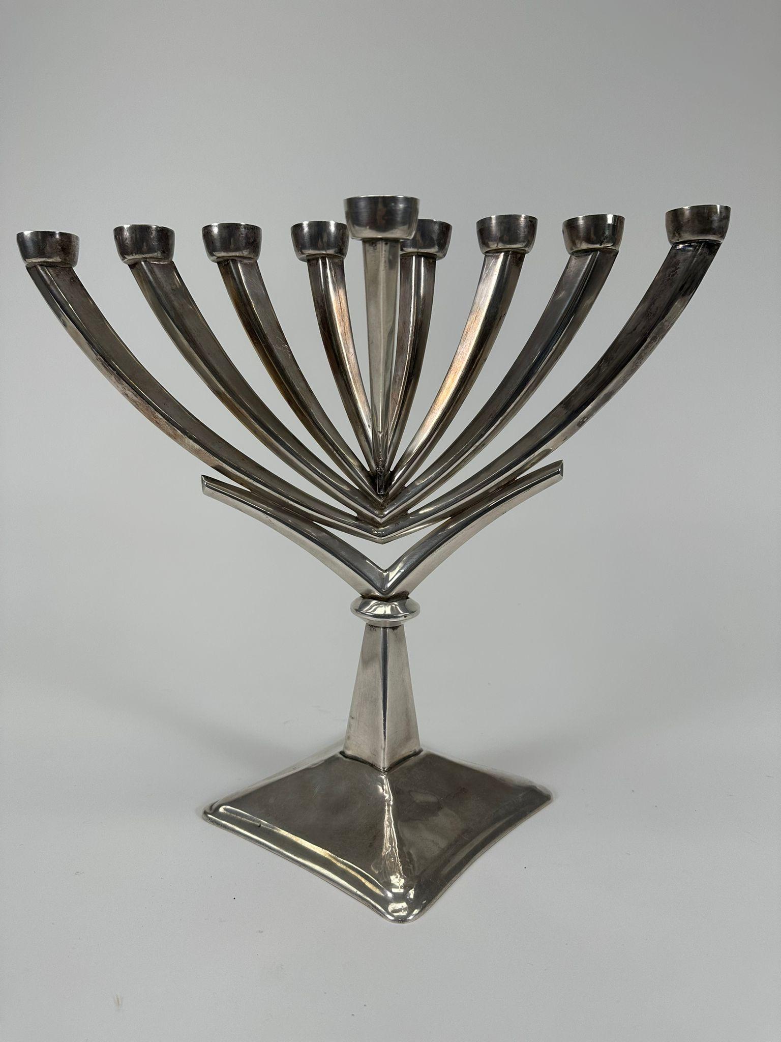 This striking 1925 German Art Deco menorah is a masterful blend of tradition and modernist design, embodying the geometric refinement and streamlined aesthetics of the era. Handmade from fine silver and marked with artisan hallmarks, this menorah is
