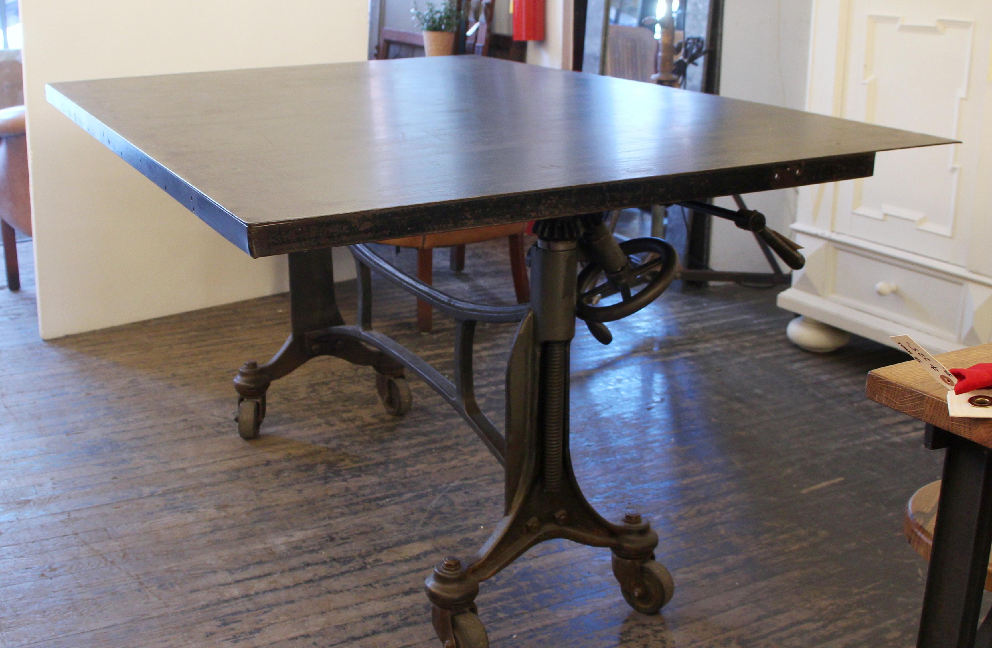 1925 Hamilton printer's table with a black finished wheeled cast iron base and steel top. Table top has two positions, flat for day to day use and vertical for storage. Height is adjustable. There are some scratches and surface wear from age and
