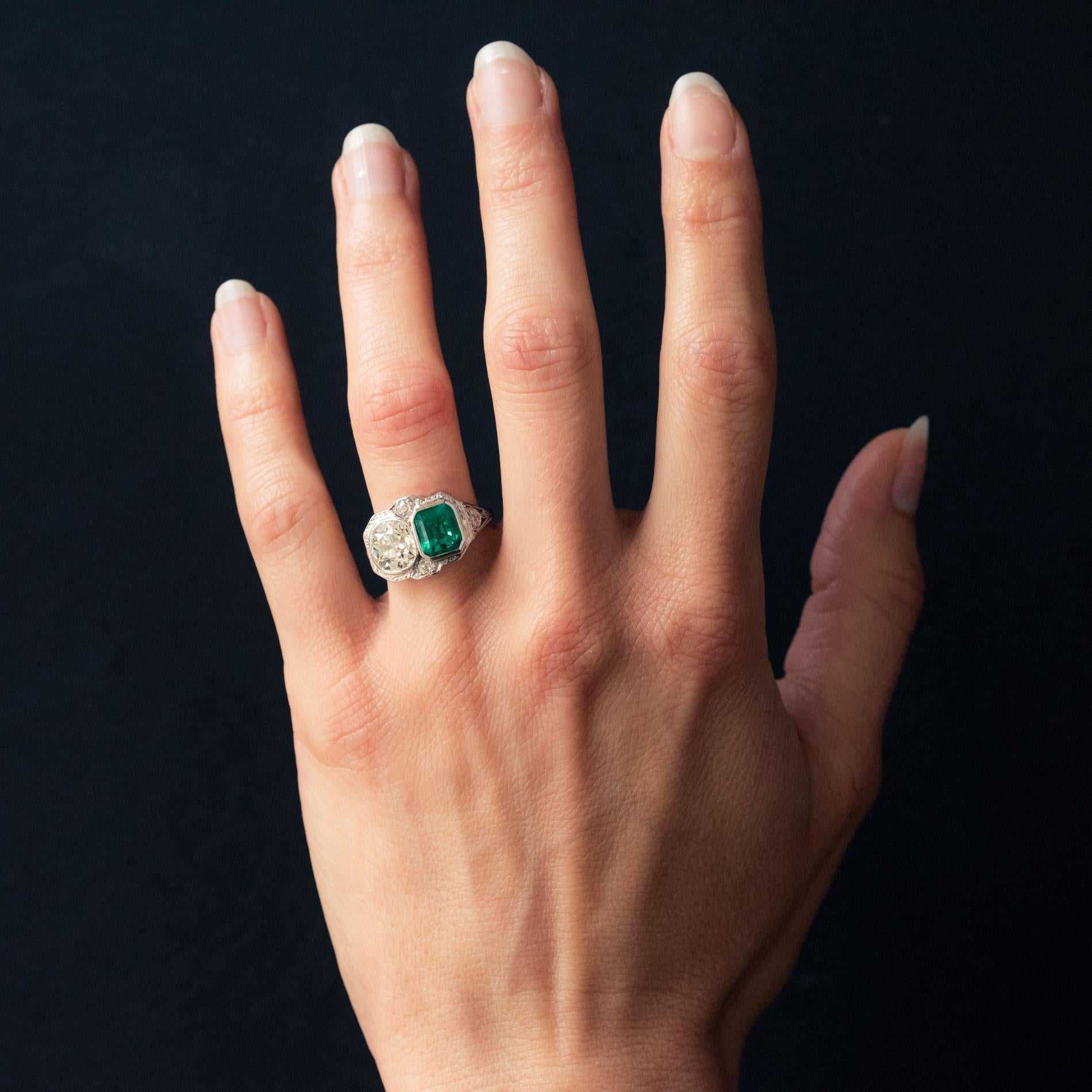 Ring in platinum.
Sublime art deco ring, its entire platinum setting is closed set on its top with a Colombian emerald- cut emerald and an antique- cut diamond. This duo of gems is surmounted on either side by an antique brilliant- cut diamond. The
