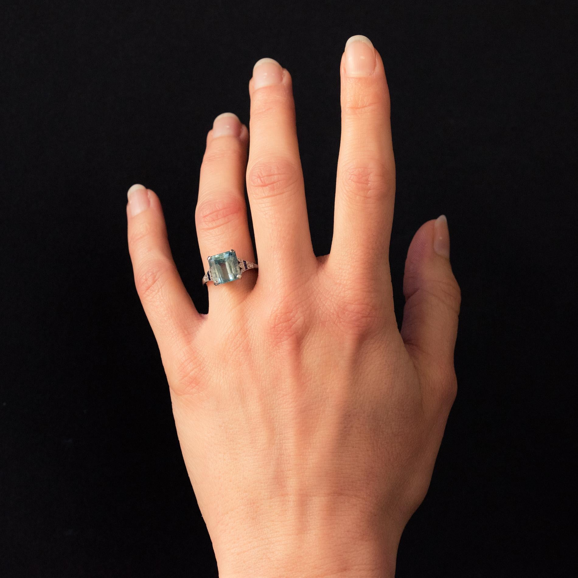 Ring in platinum.
Timeless antique ring, it is set on its top with 4 flat claws of a very beautiful emerald-cut aquamarine. On both sides the start of the ring is composed of a delicately openwork pattern and set with 2 x 4 diamonds and 2 x 2