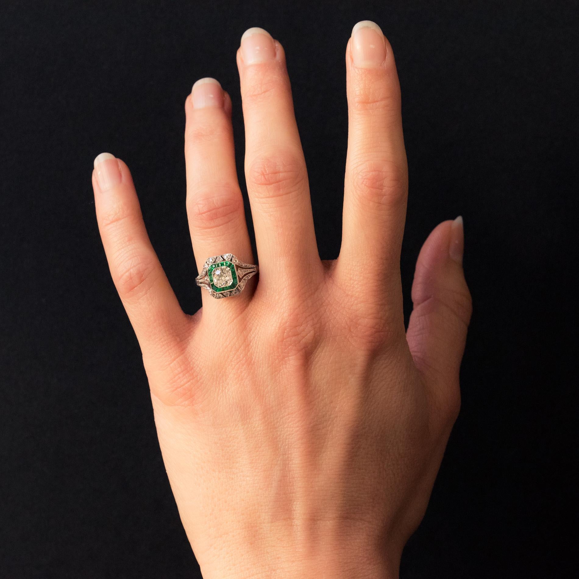 Ring in platinum.
Delicate antique ring from the Art Deco period, it is set on its top with an antique brilliant-cut diamond in a hexagonal millegrain decor and surrounded by a row of calibrated emeralds. The platinum setting is perforated and set