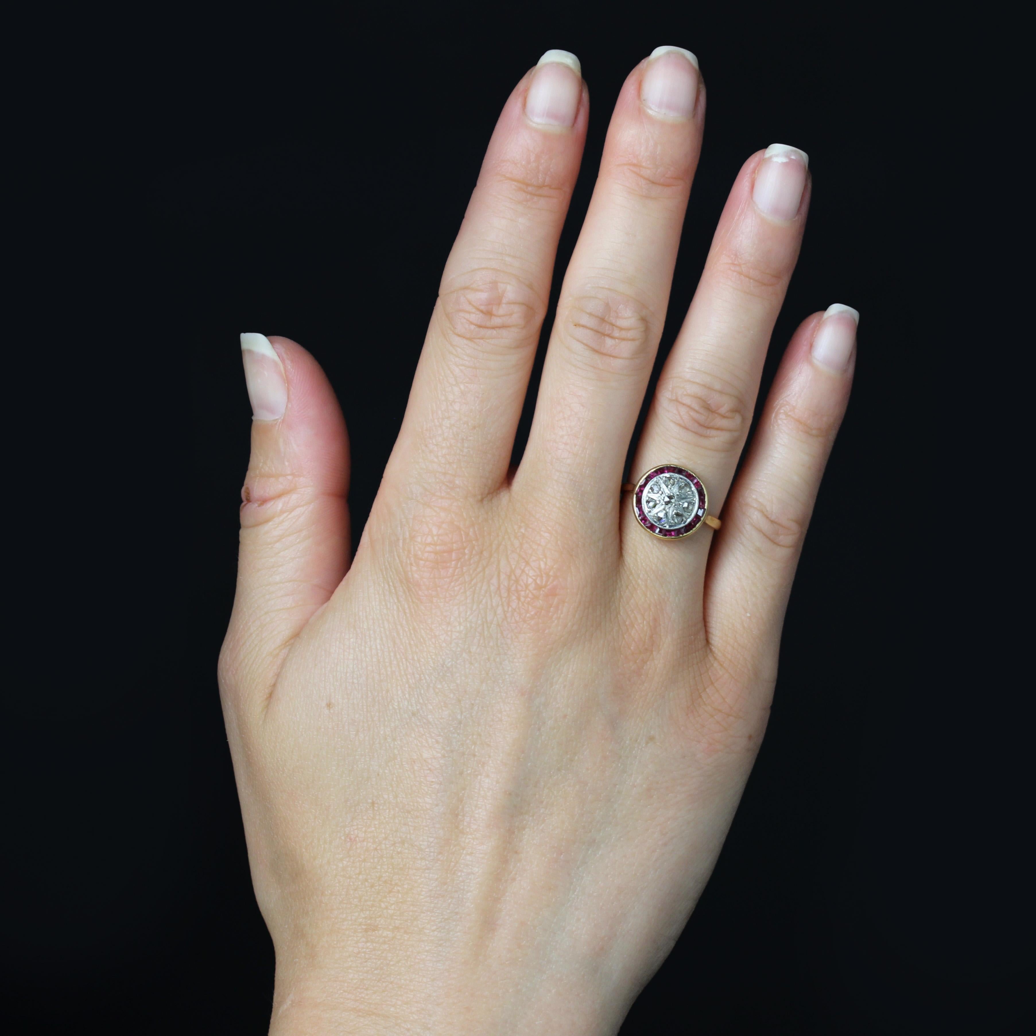 Ring in 18 karat yellow gold.
Antique Art Deco ring, the round setting is set with rose-cut diamonds in a radiant motif in the center on platinum, surrounded by calibrated red gems in a rail setting. The basket is openwork on the underside.
Diameter