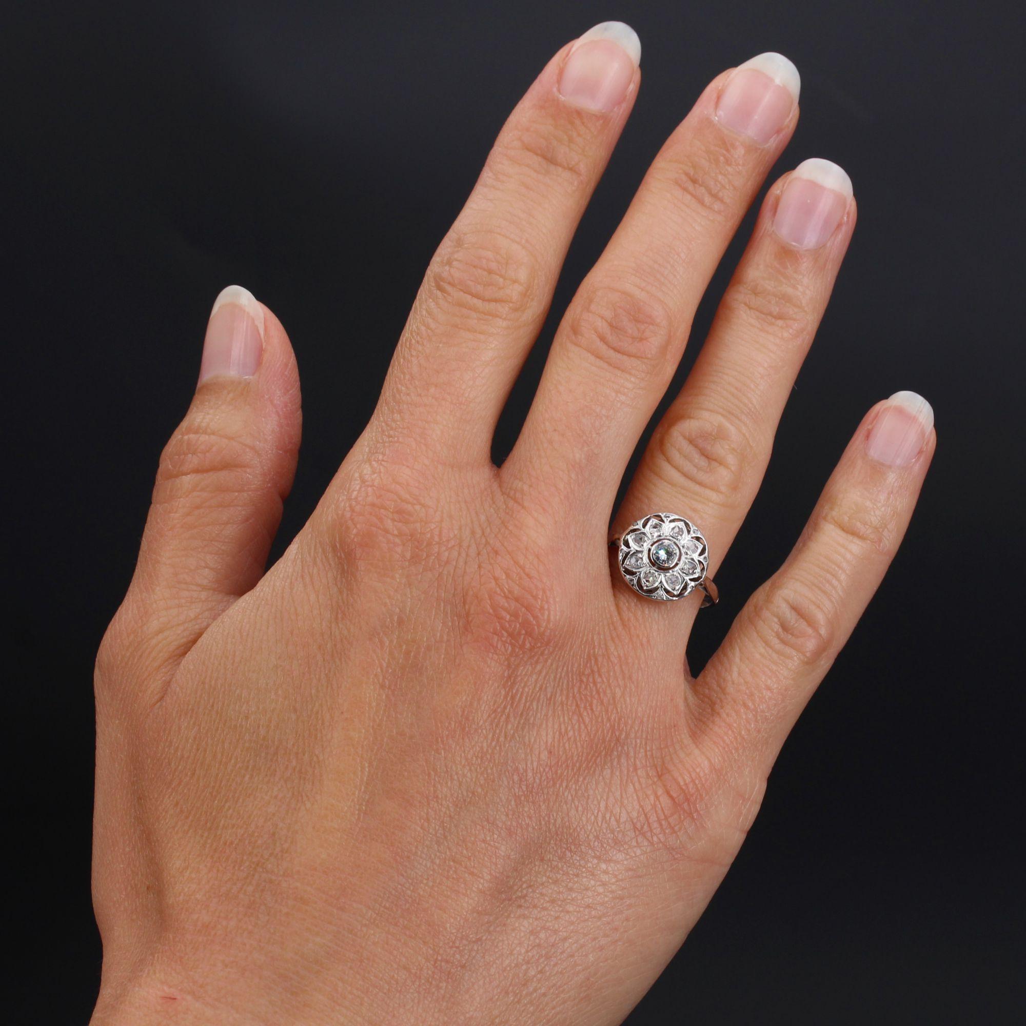 Ring in 18 karat white gold.
Of round shape, this charming antique ring is closed- set in the center, of a brilliant- cut diamond, on a decoration openworked like a flake set with rose- cut diamonds. All around the tray is also sprinkled with small