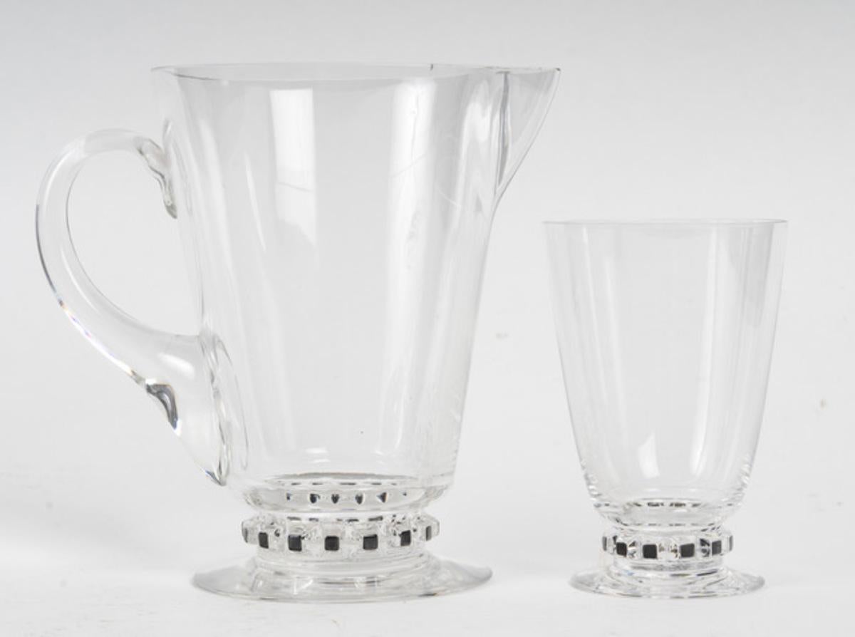 René LALIQUE (1860-1945), France, “UNAWIHR” model, Set of six glasses and a jug in blown-molded white glass, base decorated with black enamel geometric pattern. 
Signed “R.Lalique France”
Model created in 1926
Glasses: H. 5.1 in., diam. 3.5 in.
Jug: