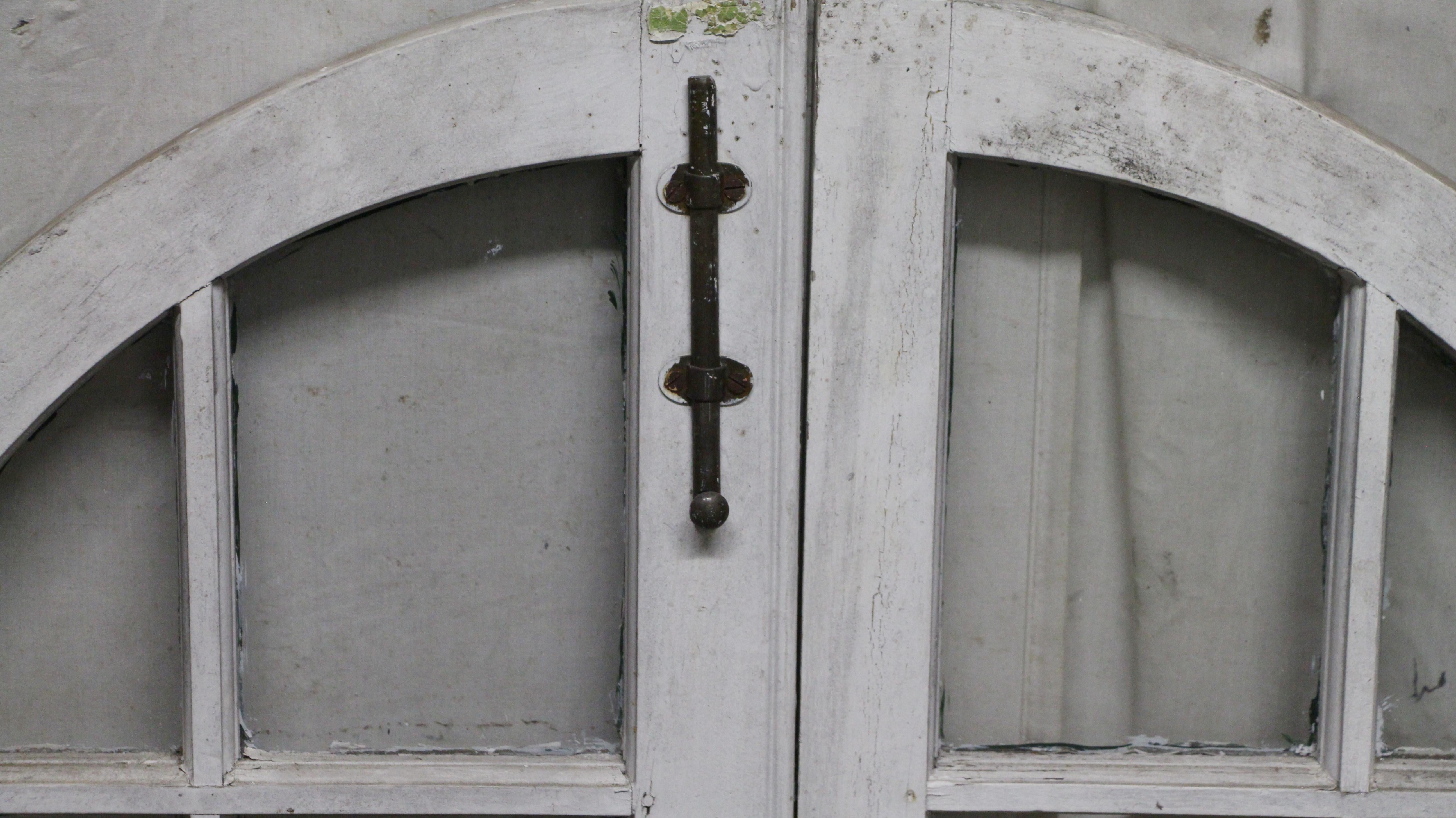 Unique pair of arched wood framed windows from the 1928 Rose Hill, the Tudor Mansion of American impresario Billy Rose. One side of the frame is painted green and the other is painted white. The original solid brass hardware is included. Priced as a