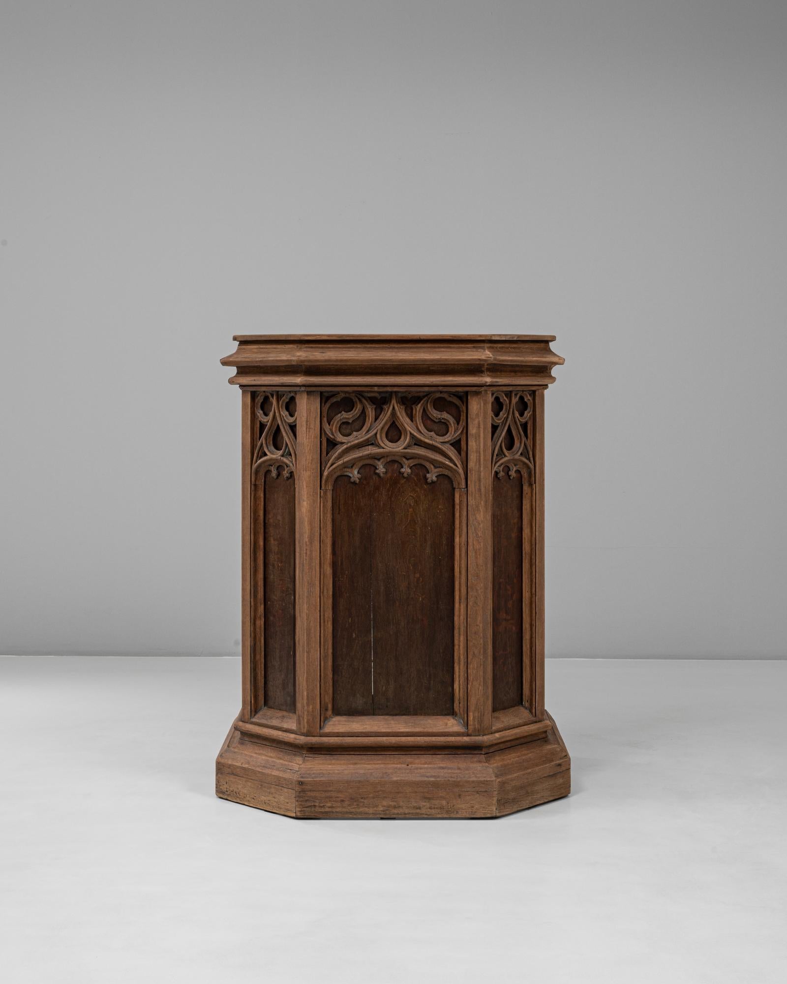 Cette chaire en bois de style néo-gothique français de 1928 reflète l'esprit architectural dramatique de ce style, alliant une forme ecclésiastique à des détails finement travaillés. Construite en bois massif avec une patine chaude et usée par le
