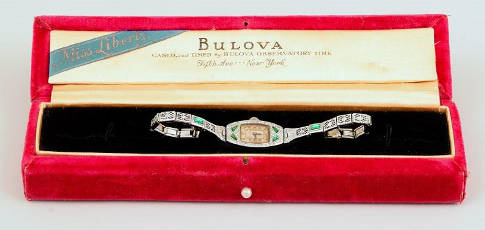 1929 BULOVA 'Miss Liberty' Ladies Art Deco Watch, featuring simulated green gems.
The watch houses an early 6AP manual wind caliber, running on 15 jewels. This movement is cased in a gorgeous hinged BULOVA signed 14K gold filled case in white tone