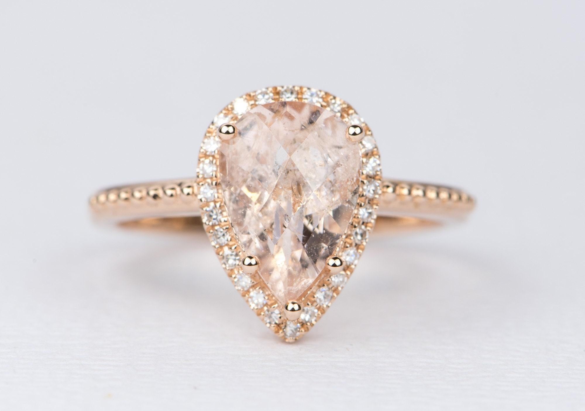 ♥  Solid 14K rose gold ring set with a pear shaped galaxy morganite in the center
♥  A diamond halo and beaded shank compliment the center stone
♥  The overall setting measures 9.43mm in width, 13.02mm in length, and sits 6.62mm tall from the