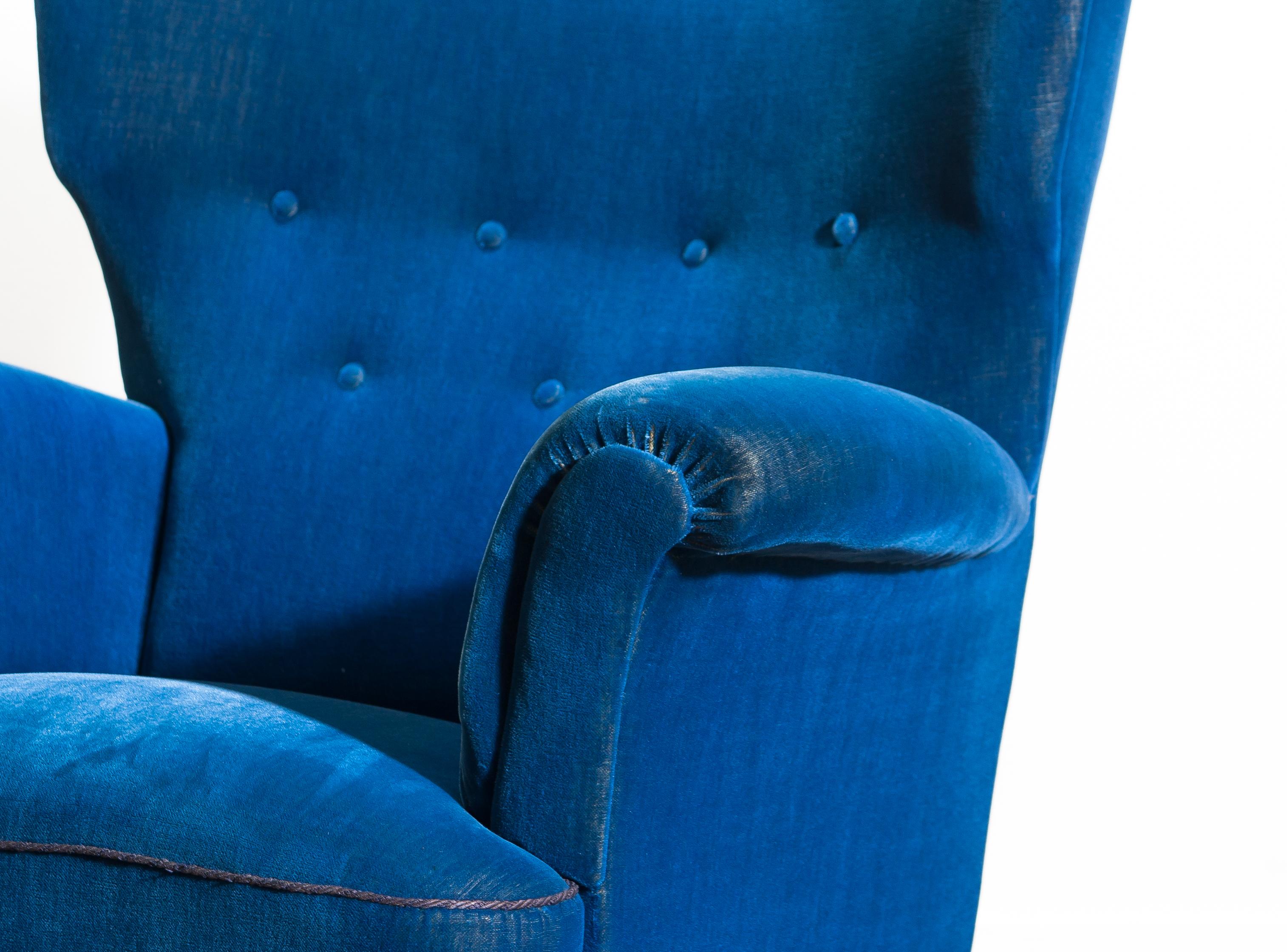 Beautiful robust 1930-1940 wingback chair in royal blue velvet and beech from Sweden, 1940s. This wingback chair is typical for early midcentury Scandinavian design.
The somewhat thin velvet gives the chair a beautiful character. Padding / springs