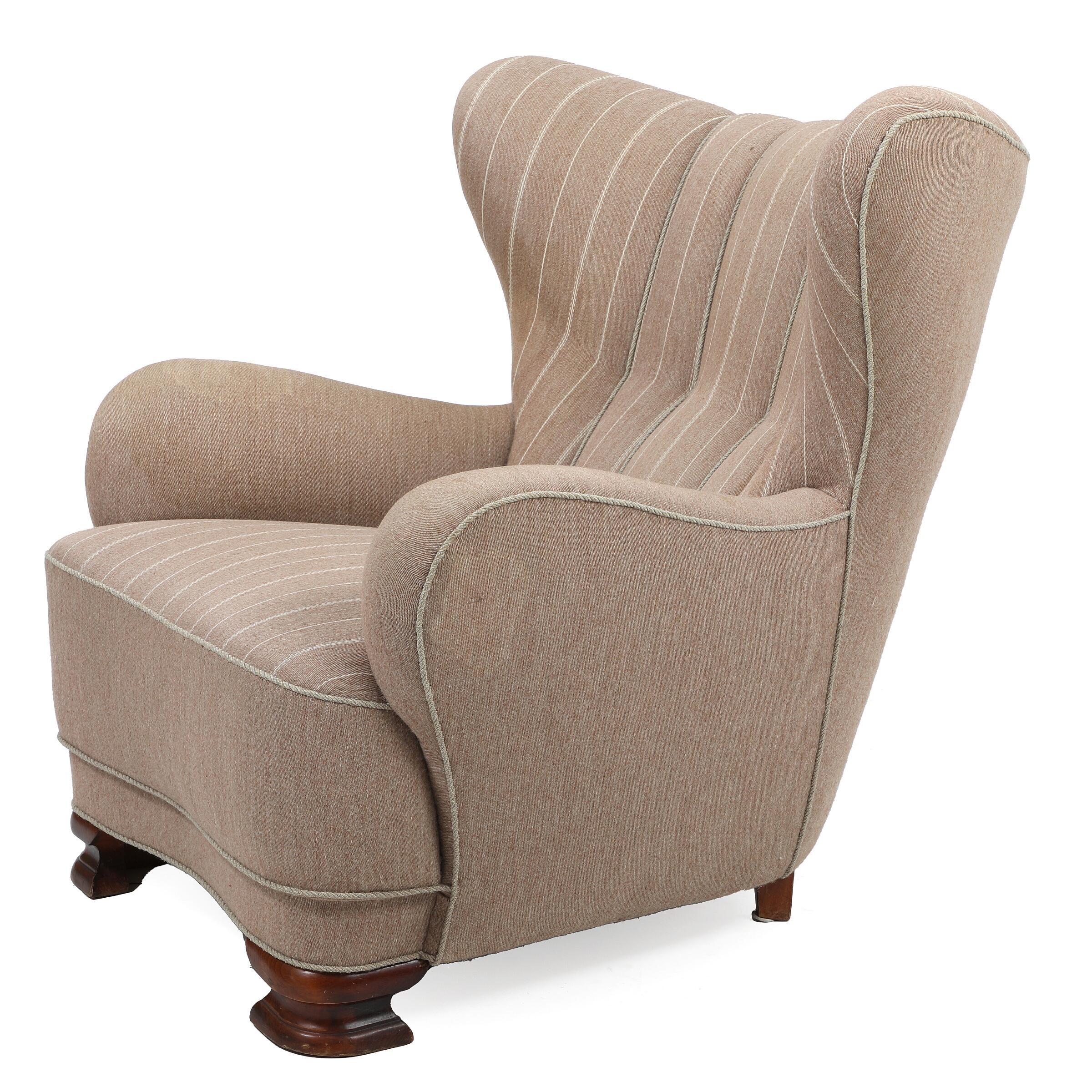 Curvy and eye-catching Danish club chair from the 1930s or 1940s. Set on feet typical of the art deco period and tapered channeled back reminiscent of sports car seats of the era. The rounded armrests are very much in the style of Flemming Lassen.