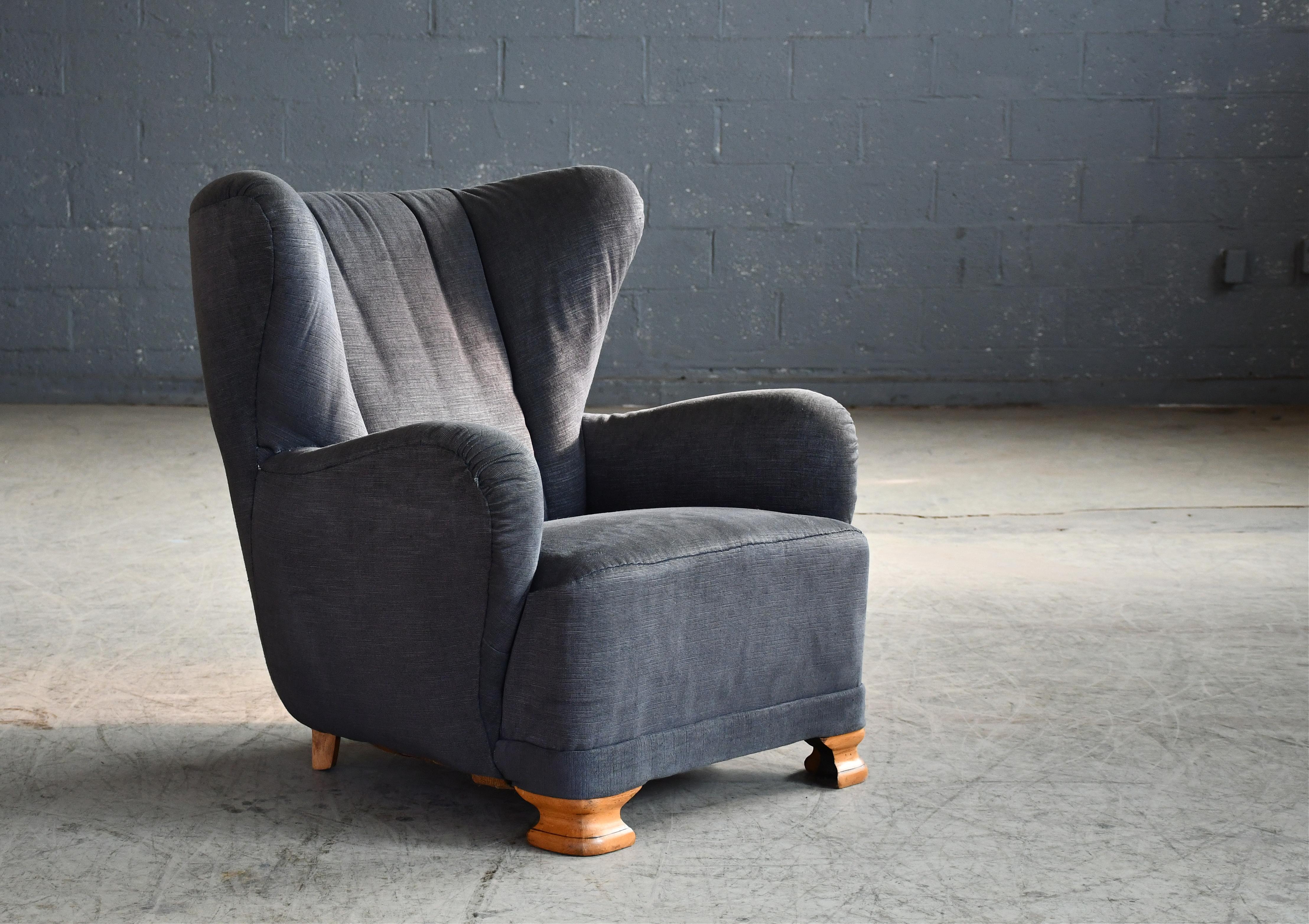 Curvy and eye-catching Danish club chair from the 1930s or 1940s. Set on feet typical of the art deco period and a winged channeled back giving the chair a lot of flair and presence. The rounded armrests are very much in the style of Flemming