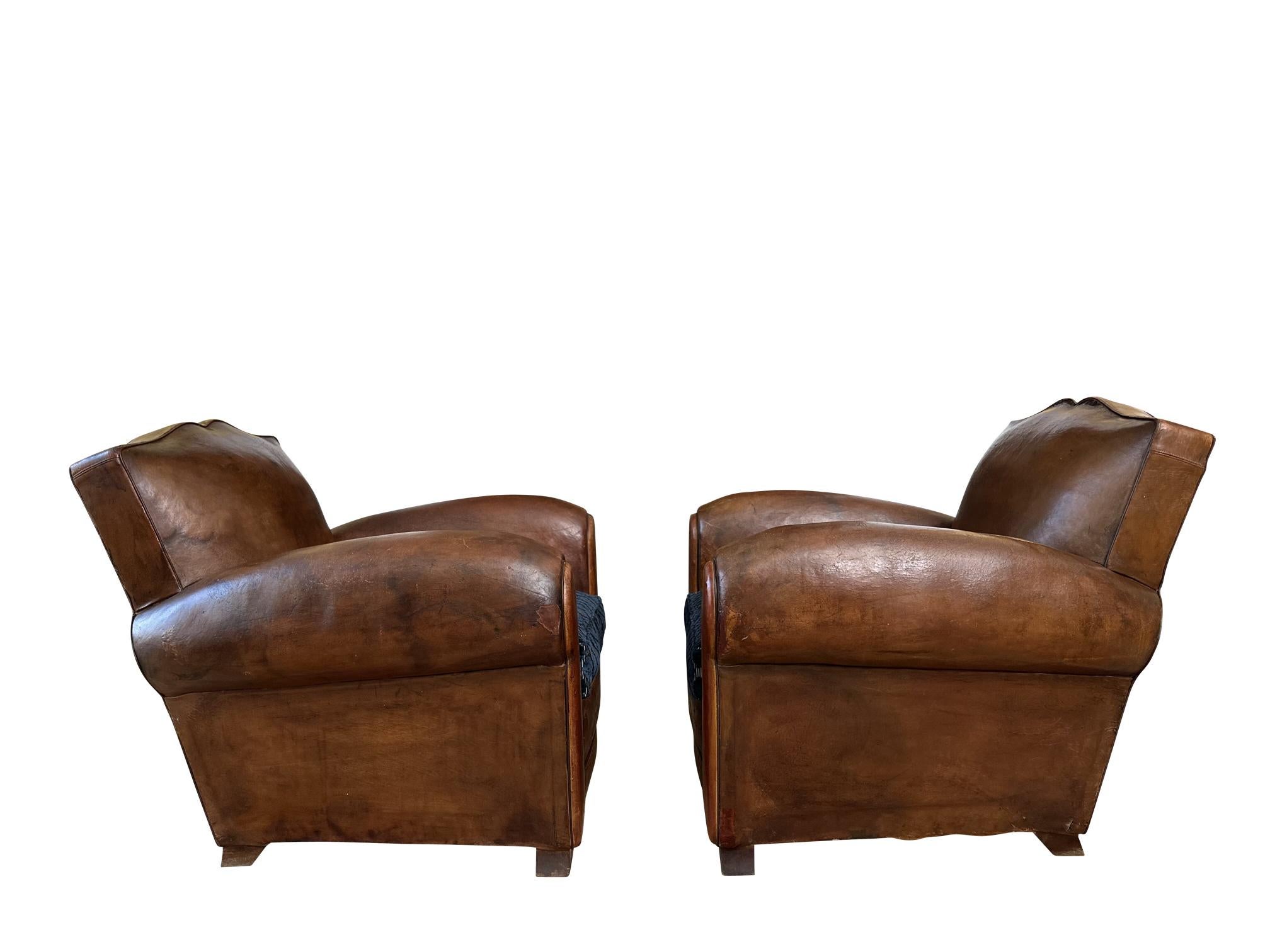 Pair of Mustache original Art Deco French leather club chairs. Circa 1930s with original leather. This is a beautiful, highly coveted Moustache clubs pair with a lot of character and charm. Extremely comfortable. In good general condition with wear