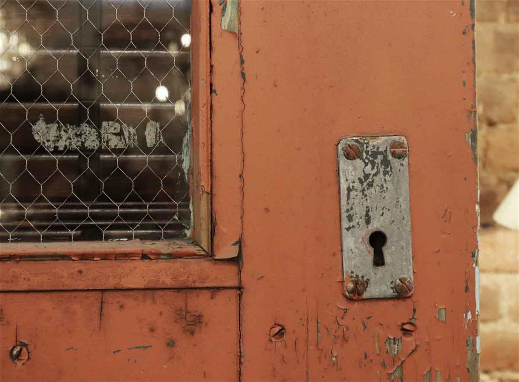 From 1930. Four chicken wire glass windows enhance this solid wood exterior Arts and Crafts exterior industrial door with original paint. The exterior has two decorative raised braces with steel rivets. It is pinkish orange on one side and aqua blue