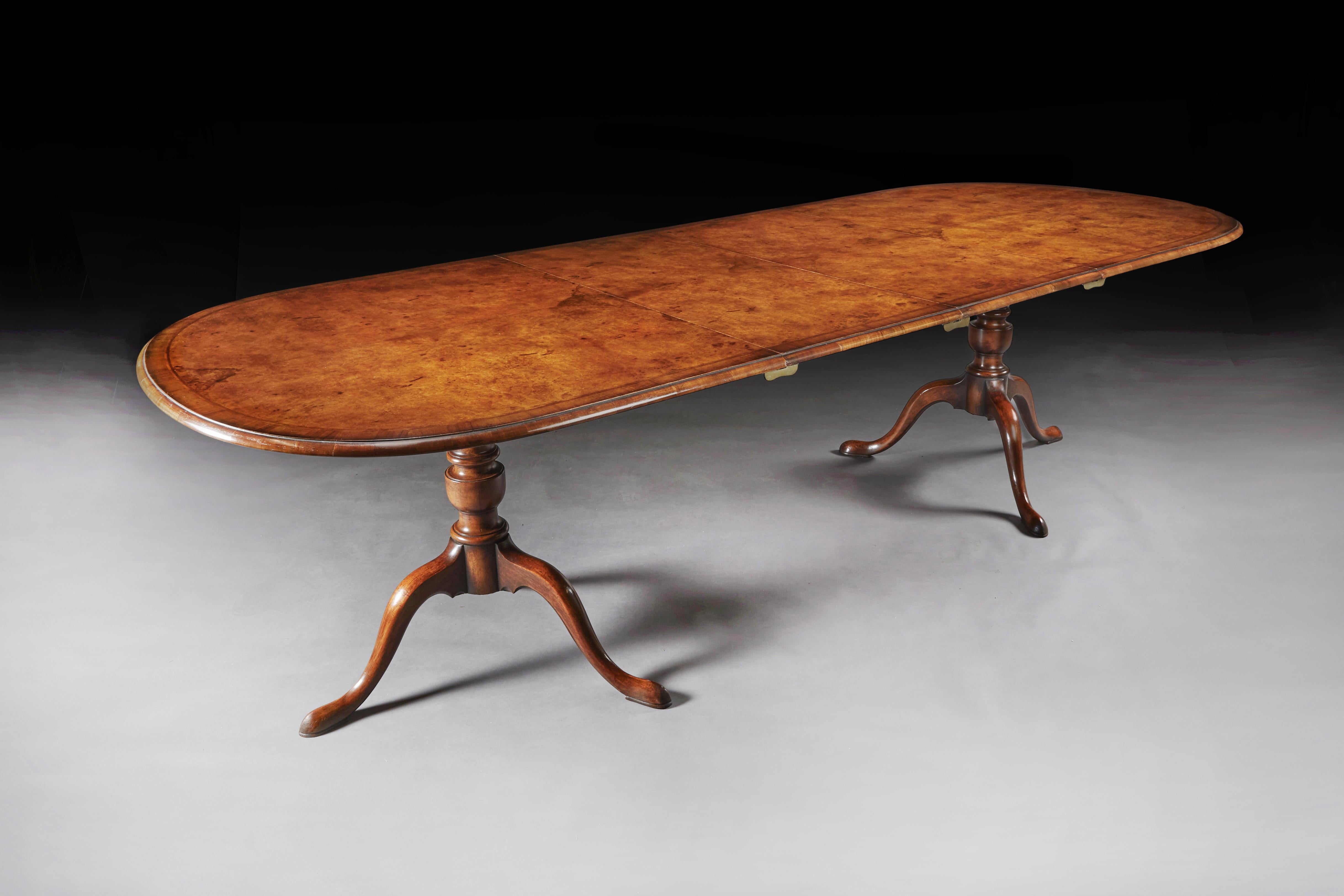 A good quality 1930s two leaf burr walnut extending twin pedestal dining table. 

English, circa 1930.

The D-ended shaped top veneered in burr walnut, with two additional leaves, crossbanded with a herringbone inlay and endgrain moulded edge