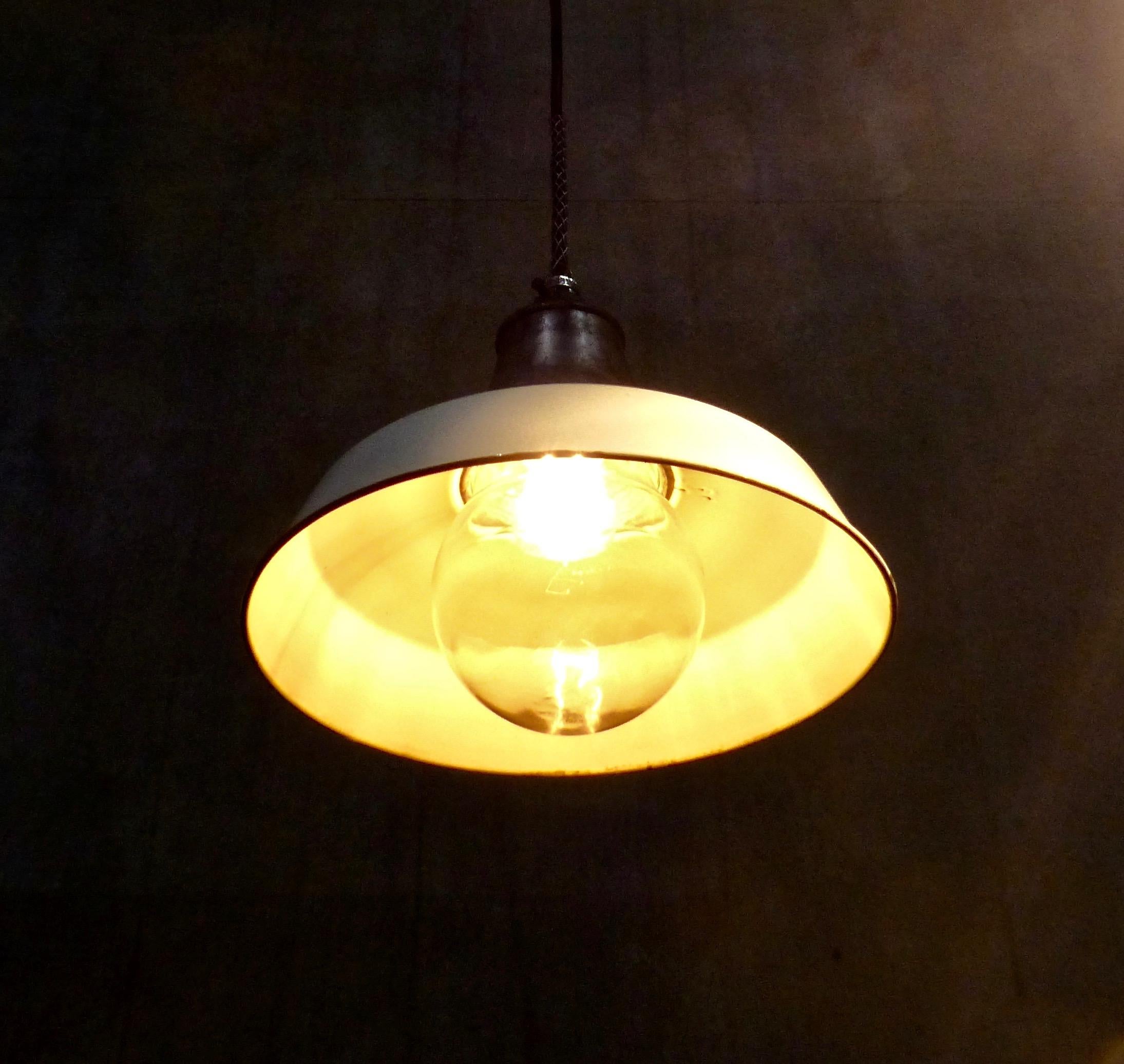Set of four cast aluminium pendant lights, circa 1940. These authentic industrial factory lights feature original white enamel shades and glass globes. Re-wired and CSA approved to current electrical standards; ceiling mounting plate included.