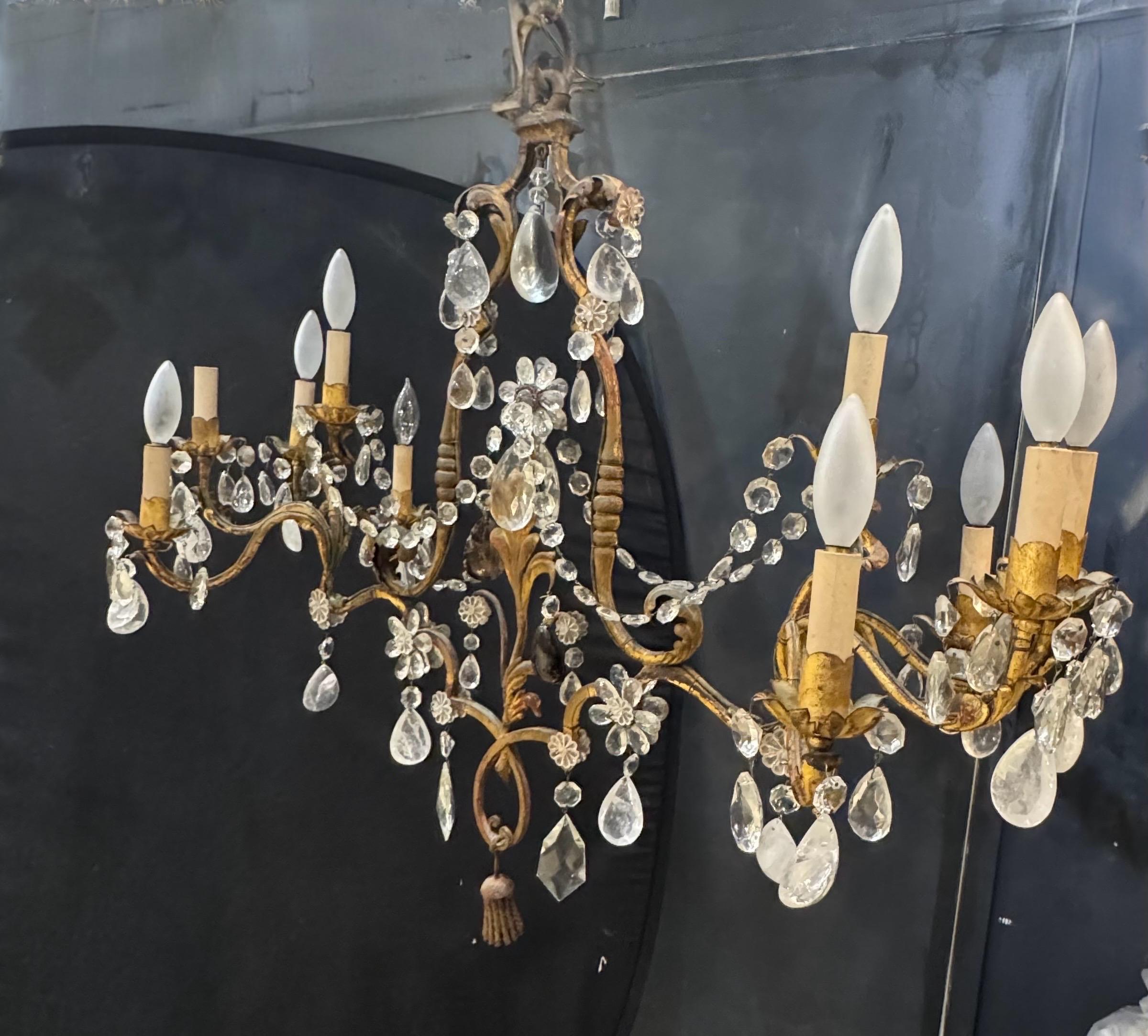 Lámpara de araña de 10 luces de metal dorado Bagues francés de forma muy inusual. Tiene forma plana ovalada en el centro y diseño de brazos enrollados en los laterales, cristales de roca colgando por toda la araña.
