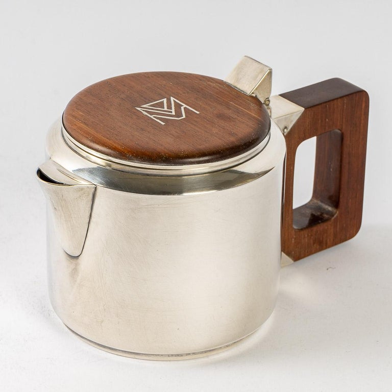 Tea and coffee egoiste set in sterling pure silver and rosewood by Jean E. Puiforcat created in the 1930s.

Service including:
- a coffee pot : 9 cm x 9 cm
- a teapot : 8 cm x 10 cm
- a milkpot : 5.5 cm x 5.5 cm
- a sugar pot : 6.5 cm x 9