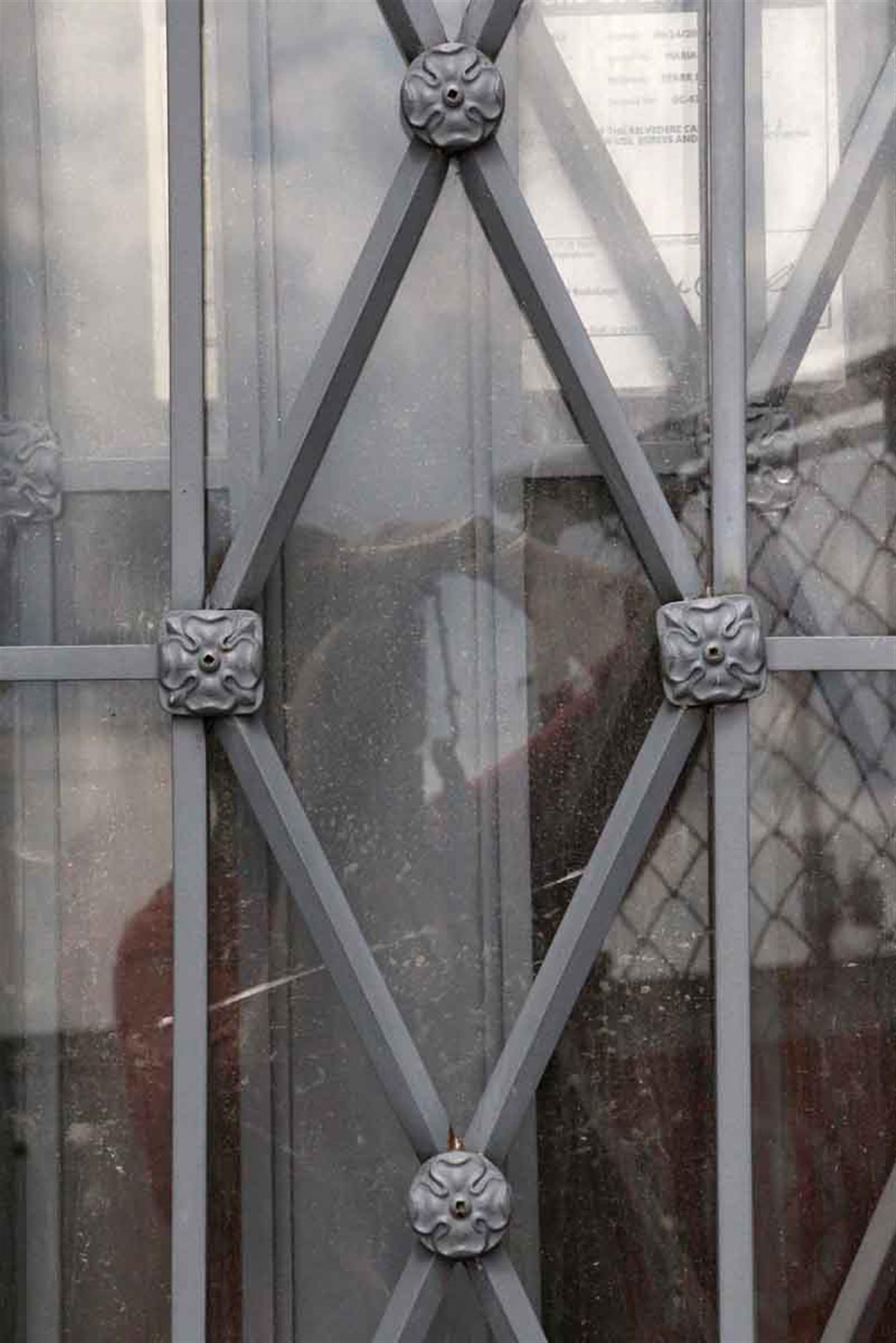 This door is from a 1930 building in upstate New Jersey. The glass is in good condition with a diamond lattice design that is finished with floral rosettes. Several doors available at time of posting. Some doors have damages and rust on the frame.