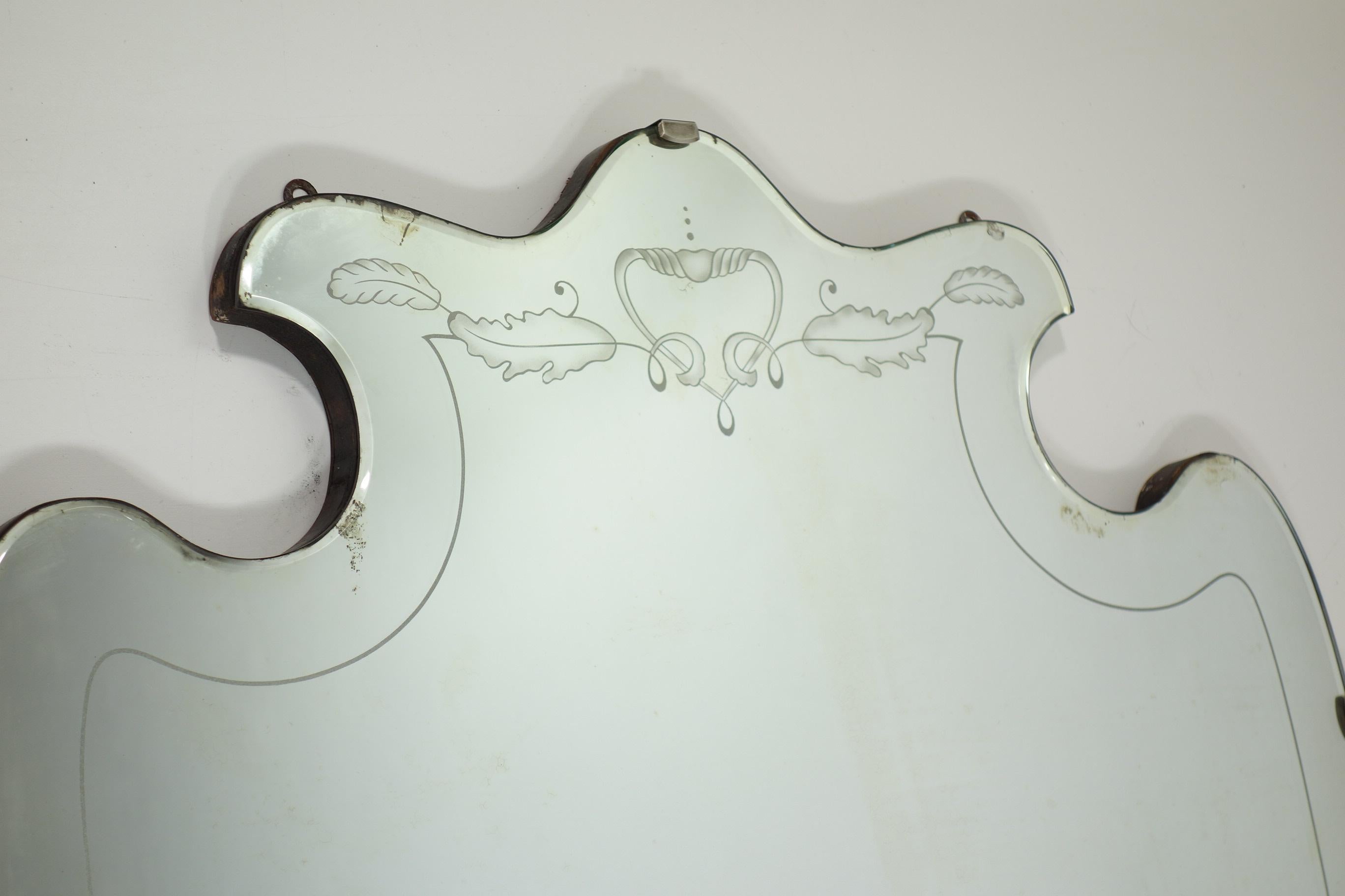 Este excepcional espejo de pared vintage, diseñado por Pietro Chiesa para Fontana Arte, muestra la elegancia atemporal y la artesanía sinónimo del Art Déco y el Modernismo italianos. Con una distintiva silueta en forma de escudo y bordes