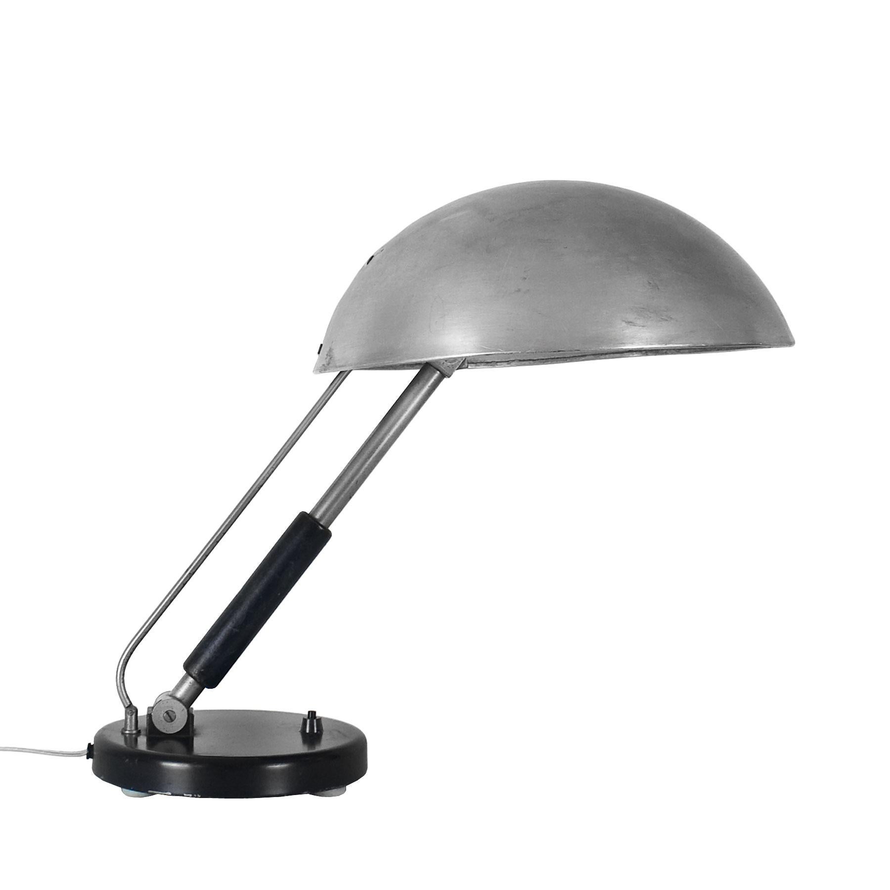 Bauhaus style desk lamp, steel and wood base and adjustable stand, aluminum lampshade.
Design: Karl Trabert.
Manufacturer: G. Schanzenbach.

Germany, circa 1930.
