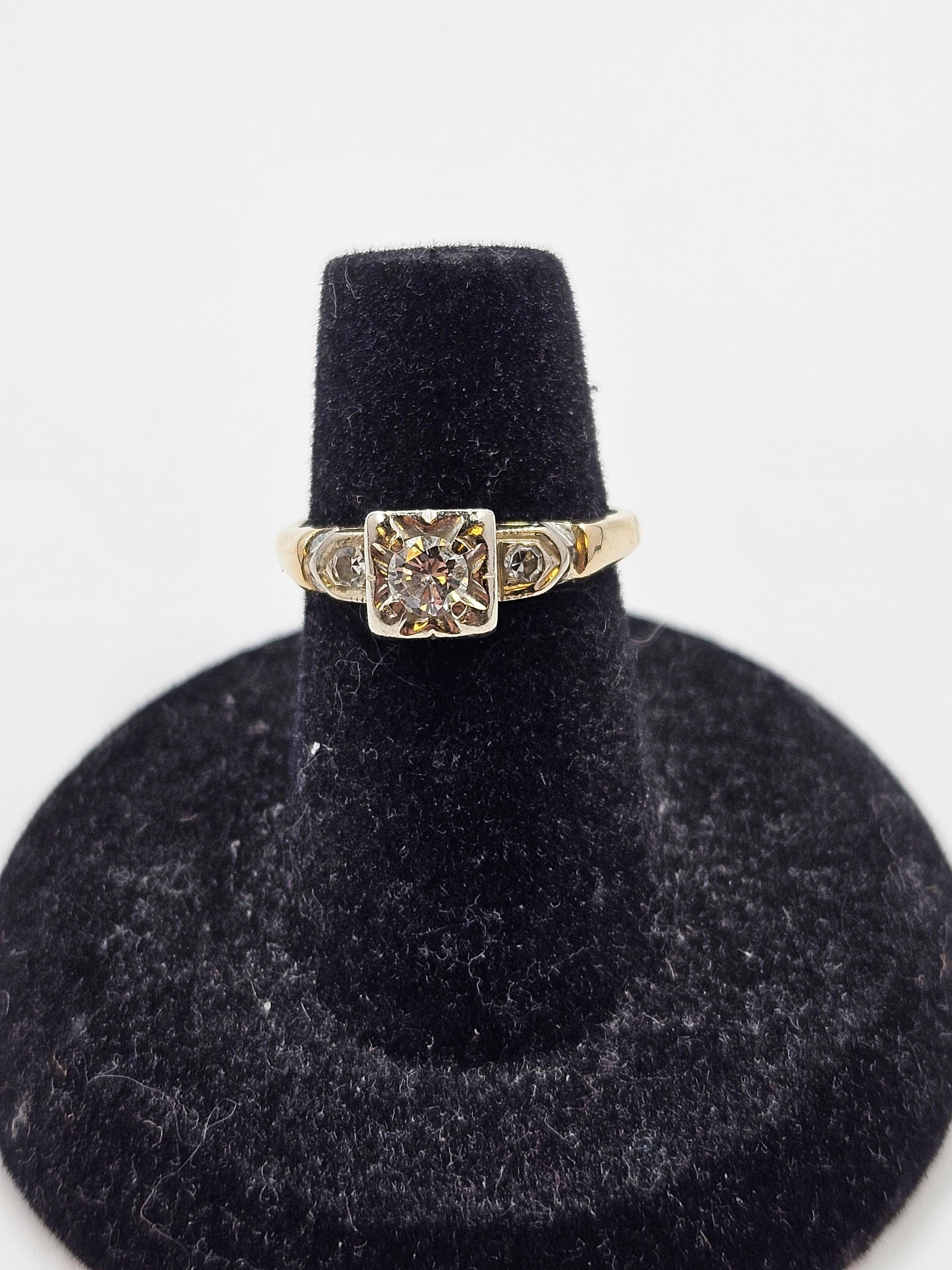 1930's 14K yellow and white gold diamond engagement ring. Head is white gold and band is yellow gold. This vintage diamond engagement ring features a 4mm round cut center stone with 2mm shoulder set round cut diamonds. The ring size is 5.5. Total