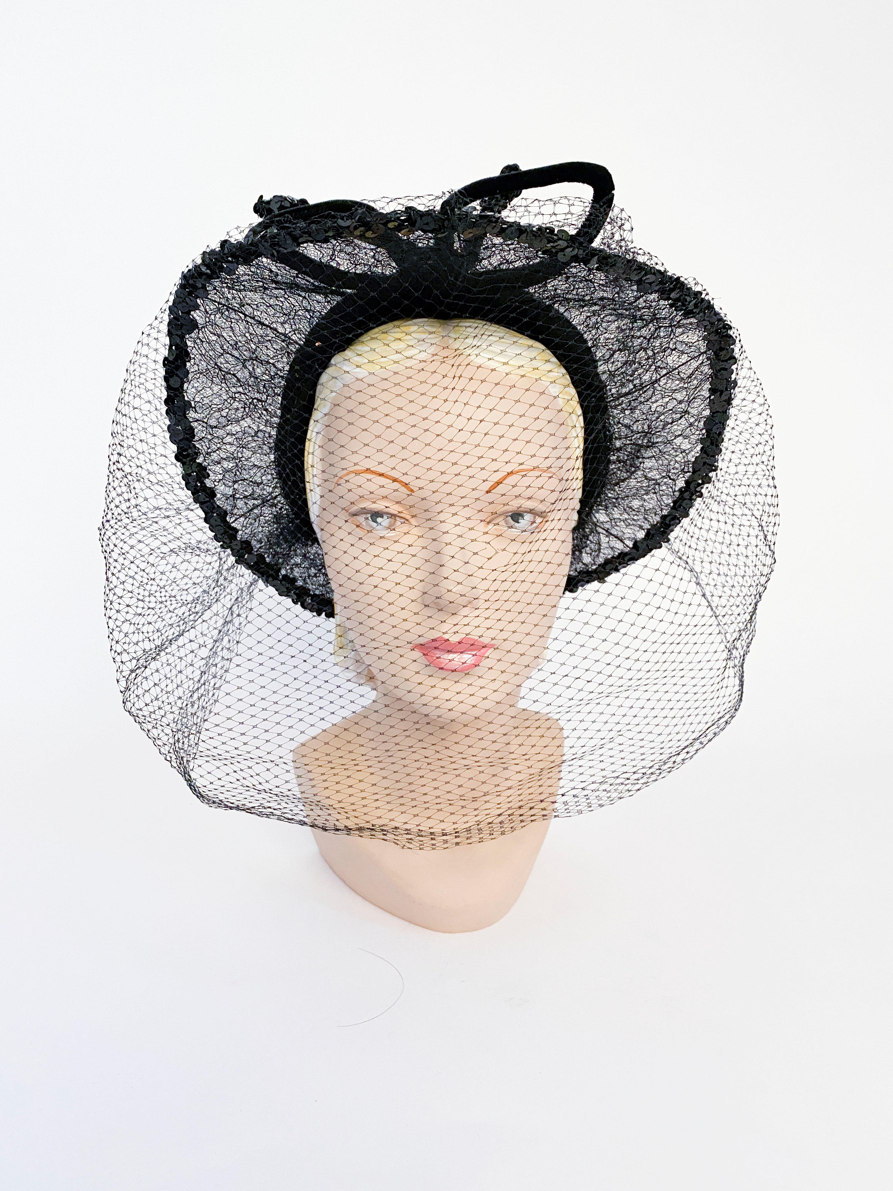 Late 1930s/ early 1940s black silk velvet hat with an extended and wired lace brim trimmed in sequin. The crown of the hat is finished with a velvet cord wired bow and a full face veil gathered in the back.