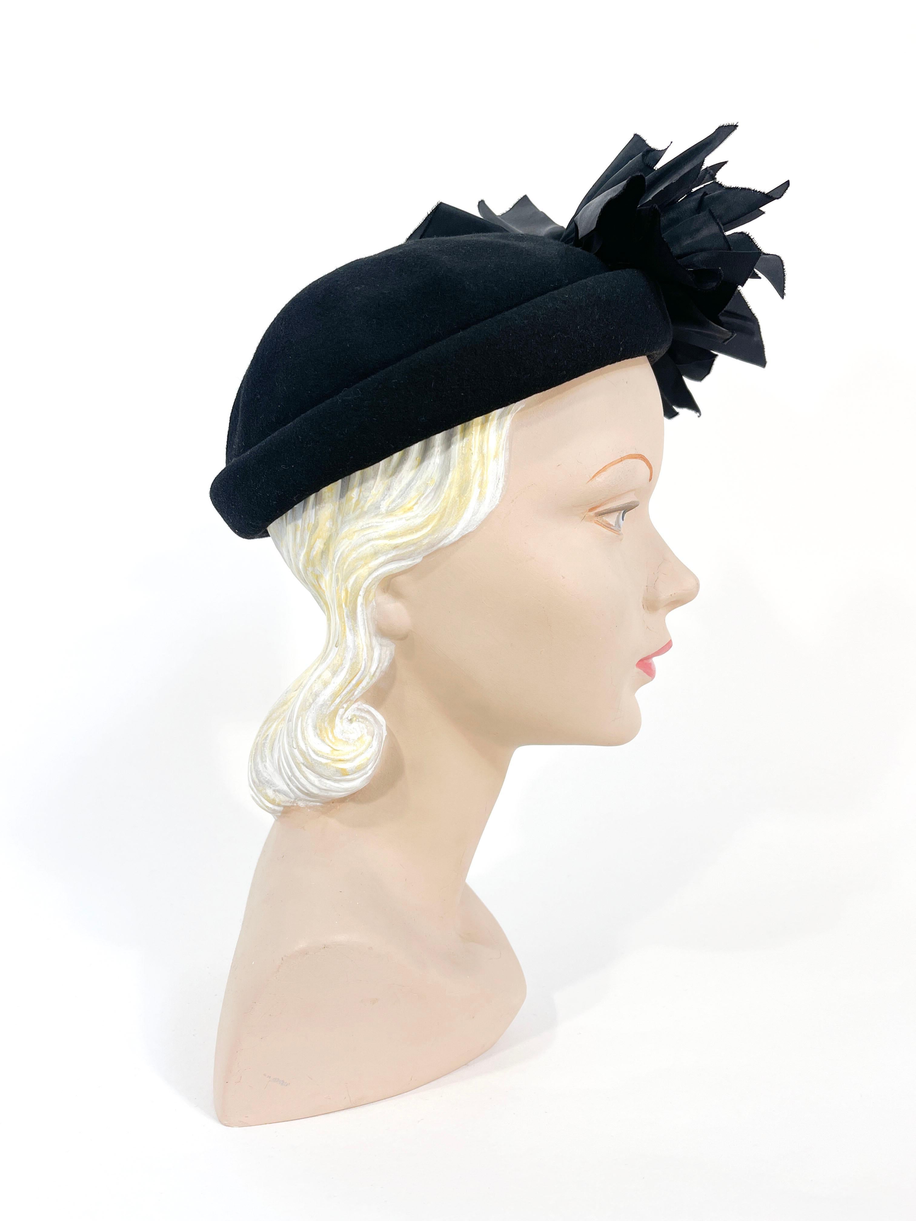 Late 1930s to early 1940s black wool felt hat with a hand rolled brim, domed crown, and an off-centered fan of gathered taffeta. The interior has a grosgrain inner hat band.

The inner circumference of this hat is 20.5 inches however it is important