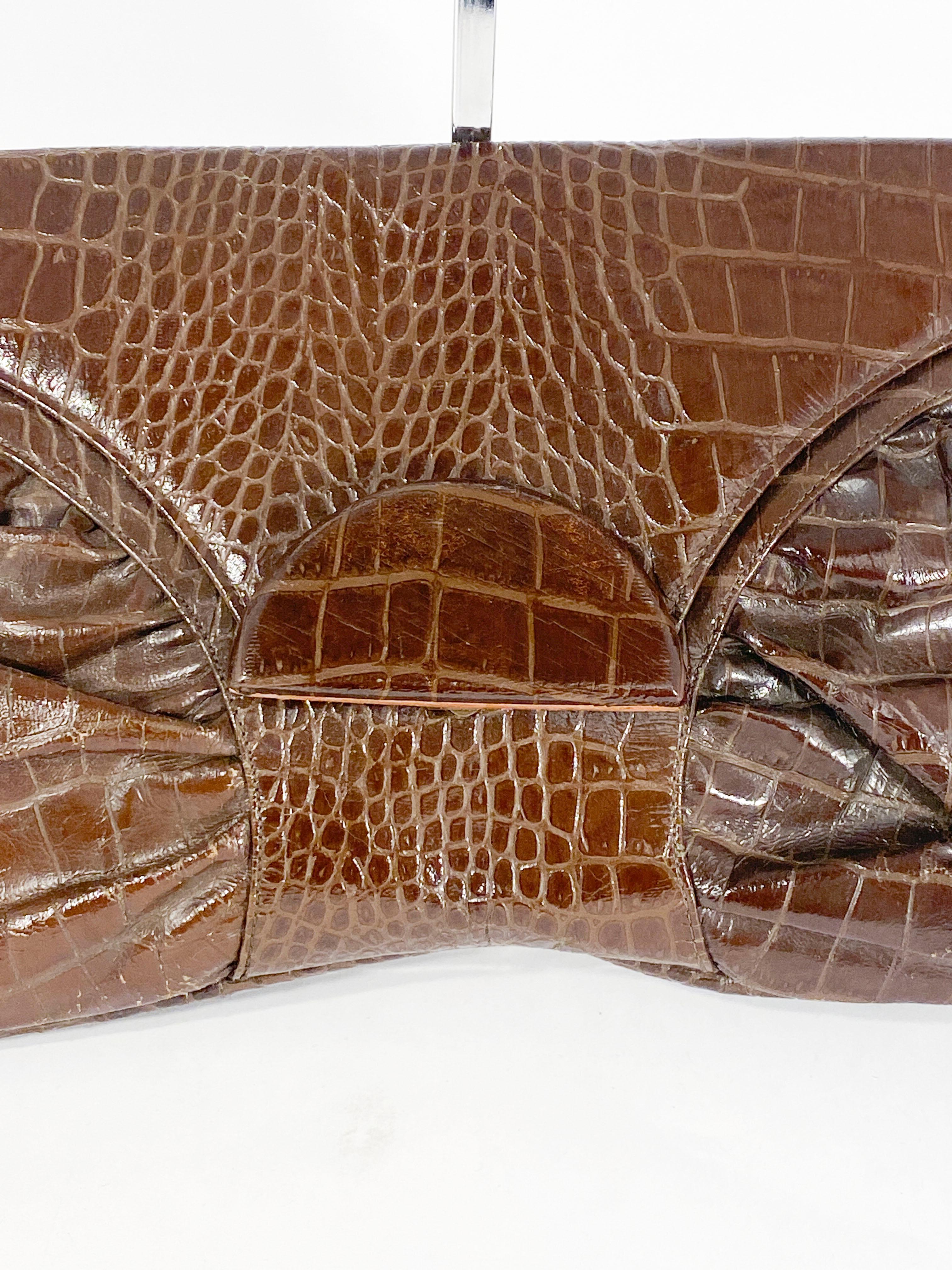 Late 1930s to early 1940s Brown oversized faux alligator envelop handbag with covered wooden clasp closure. The interior is lined with a brown twill with several pockets and a small personalized card carrier to match the purse. 