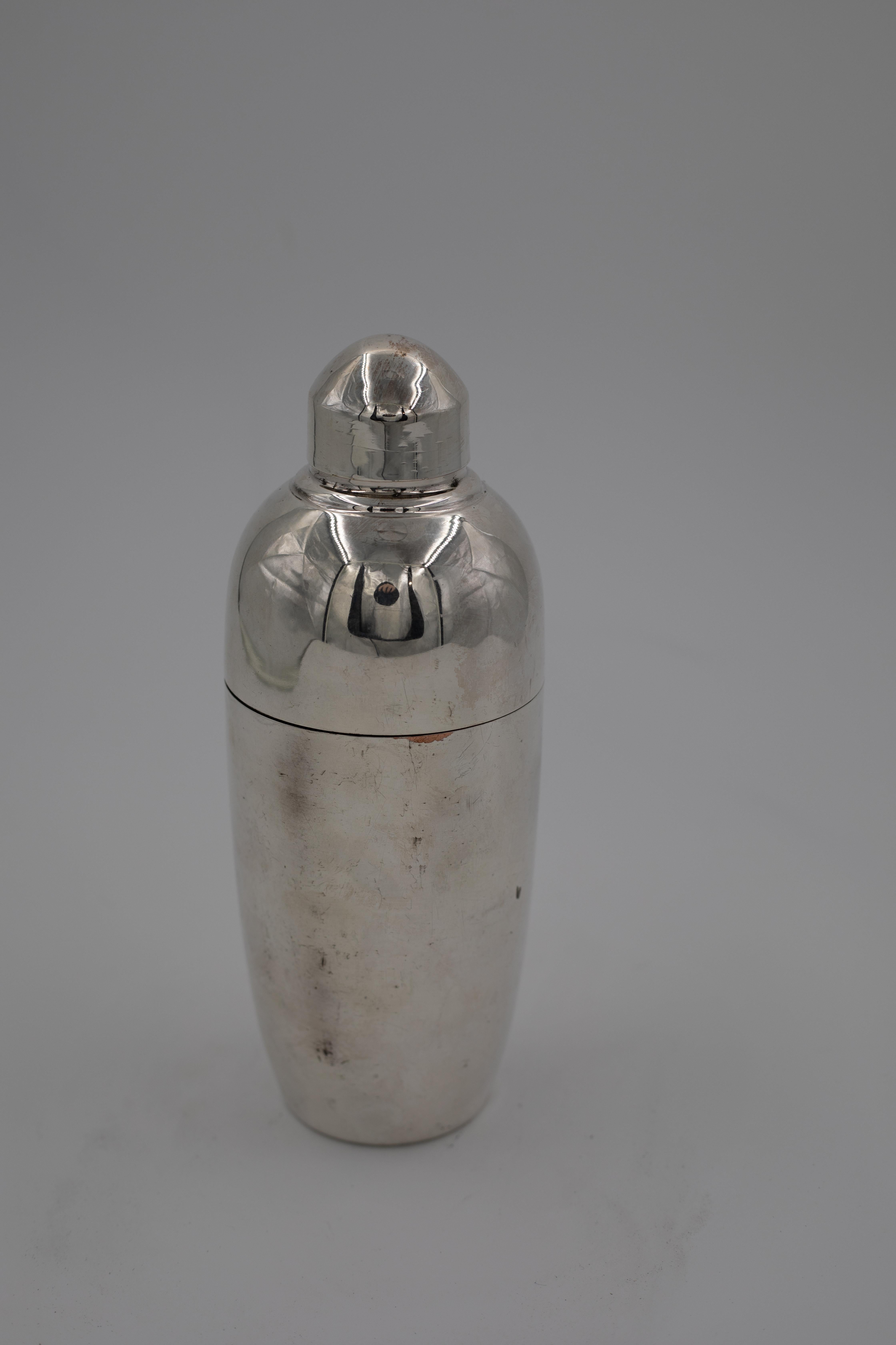 A classic vintage cocktail shaker in silverplate, dating from the 1930s–1950s and showcasing the sleek, streamlined silhouette that defined the Art Deco and early mid-century cocktail era. The shaker features a smooth tapering body and a distinctive