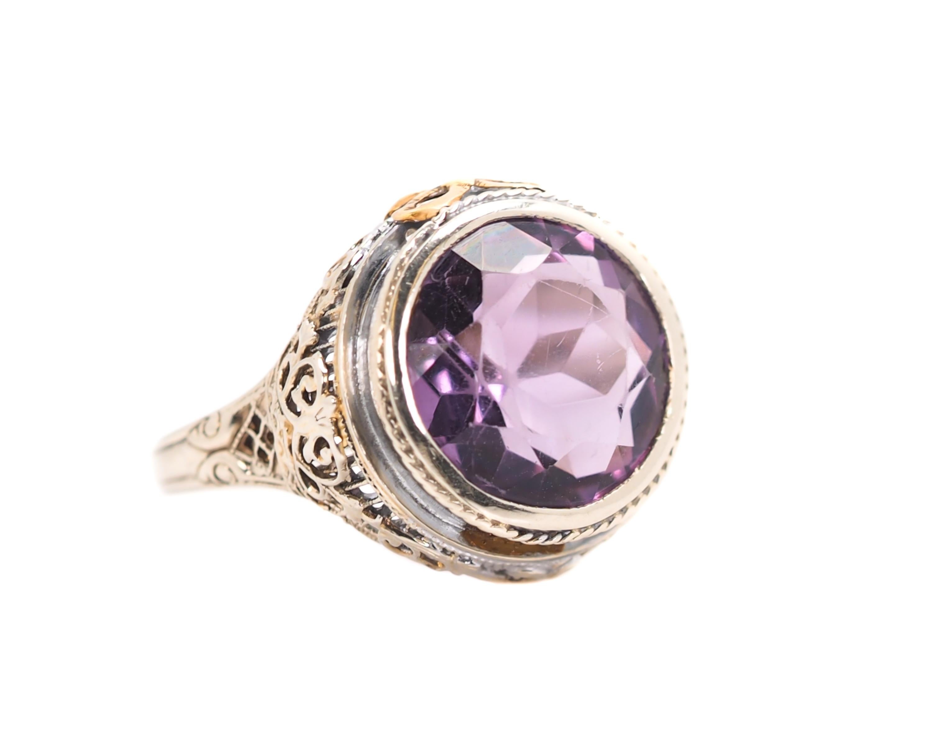 1930s Art Deco Amethyst, 14 Karat White Gold Ring

Features a 3.0 carat Round Purple Amethyst bezel set in a 14 Karat White Gold Filigree setting with a Yellow Gold Bow accent. 
The Amethyst center stone measures 13 millimeters in Diameter. 
The