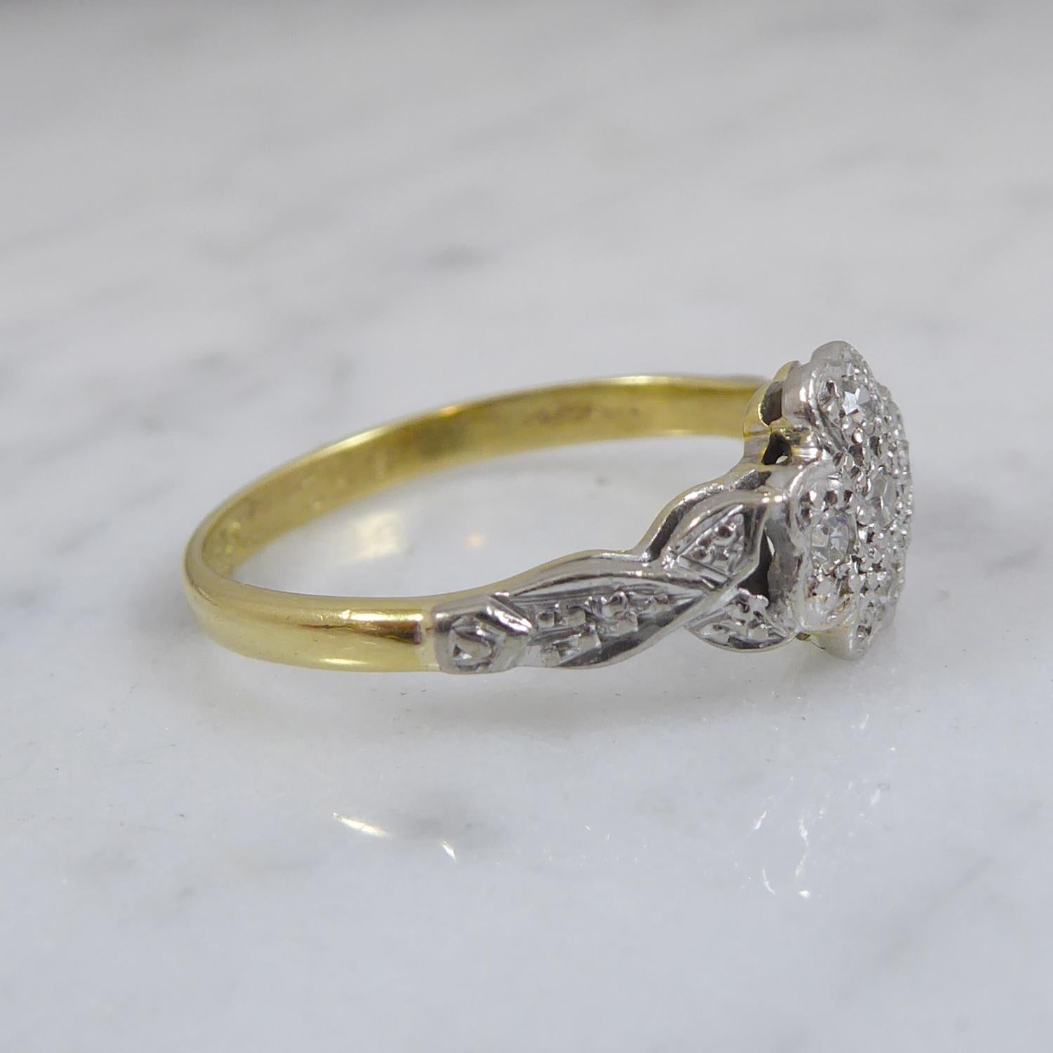 A very pretty diamond cluster ring dating from the 1930's/1940's.  In the shape of a four-petalled flower design, it features a diamond to the centre and each flowe petal is set with a smaller diamond.  A flower cluster head with millegrain settings