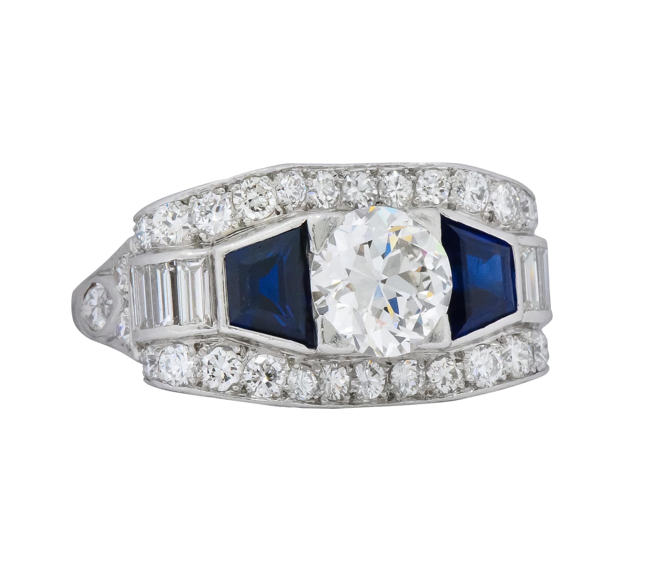 Centering an old European cut diamond weighing approximately 1.50 carats, H color and SI1 clarity

Flanked by trapezoid cut sapphires weighing approximately 1.20 carats total, bright deep blue and very well matched

Accented throughout with round