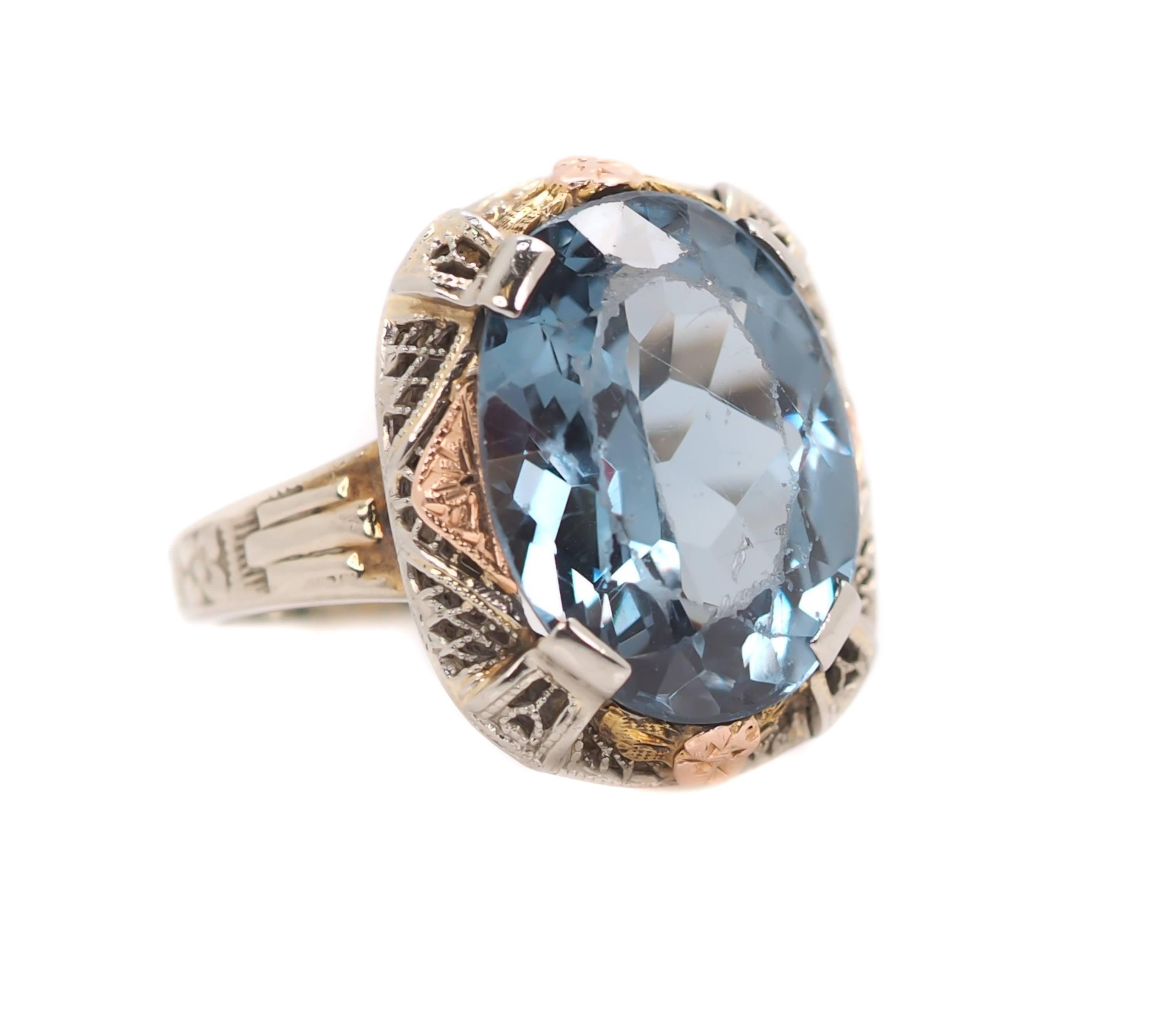 1930s Art Deco 14 Karat TriColor Gold and 5.0 Carat Blue Topaz Engagement Ring 

Features a faceted oval Ocean Blue Topaz center stone securely set with 4 prongs in a 14 karat white gold filigree mounting. The mounting has delicate 14 karat Rose