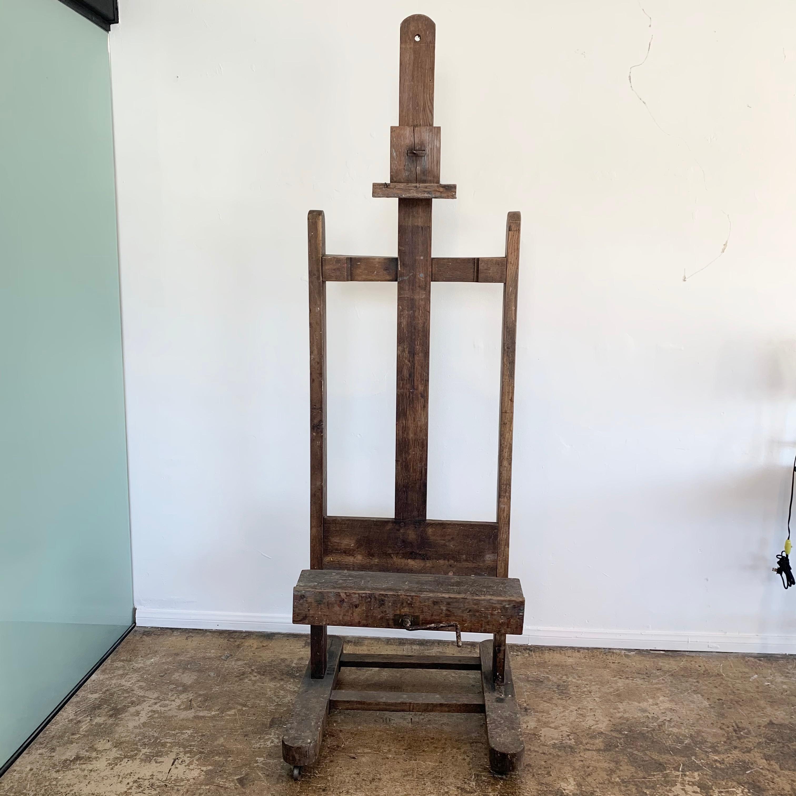 Fantastic wood easel from the 1930s. Adjustable hand crank lowers and raises the bottom of the unit. Adjustable wood piece at the top to hold the artwork or canvas. Great vintage condition. Excellent patina. Perfect for displaying a piece of artwork