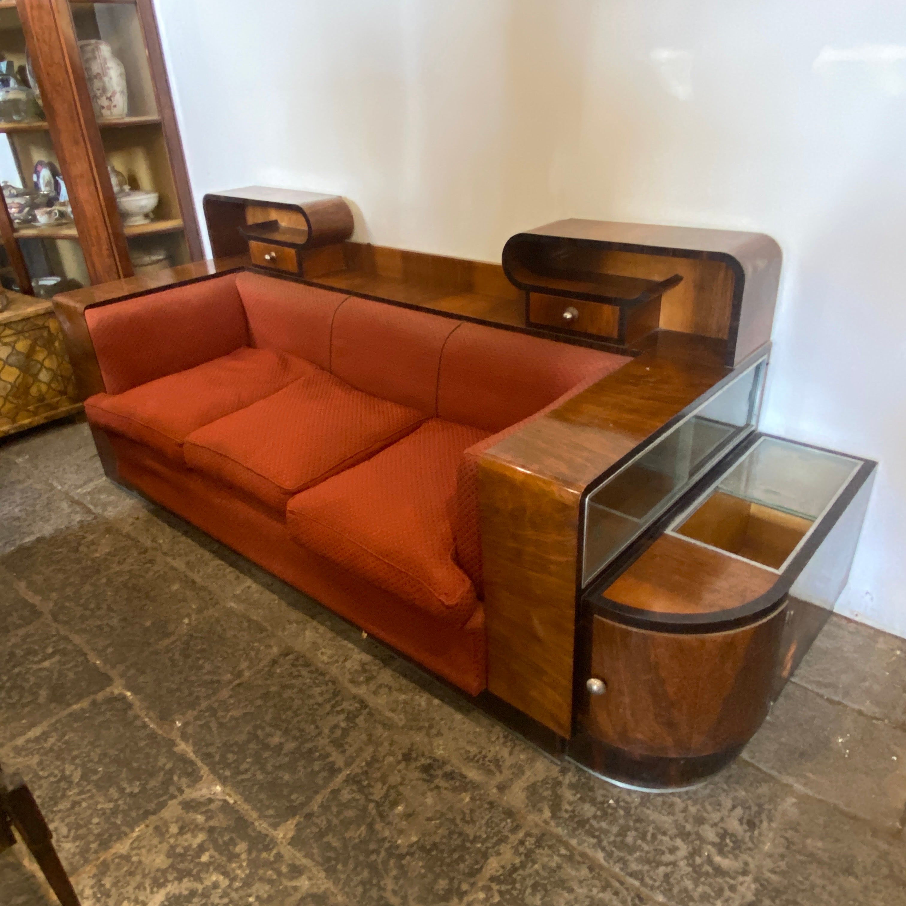 A rare art deco sofa with a bar cabinet in a side manufactured in Italy in the Thirties. It's in lovely original conditions, also the red fabric is original. It's a superb example of Italian art deco furniture.