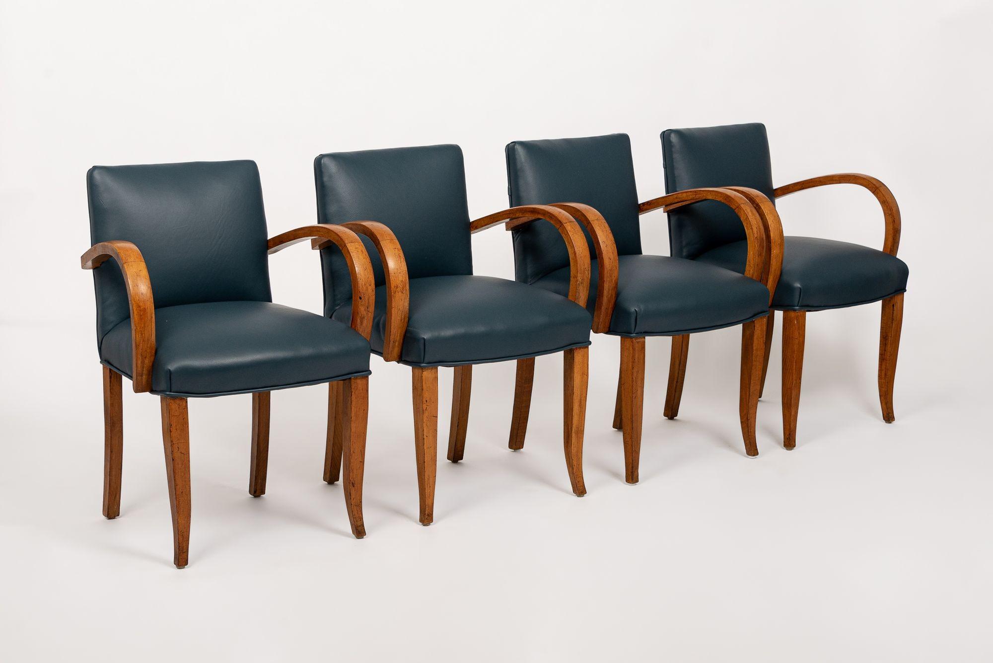 This exceptional set of four antique Art Deco upholstered dining chairs circa 1930 feature a unique and elegant design with gorgeous maple bentwood armrests and elegant solid maple wood splayed legs. The chairs have newer blue leather upholstery.