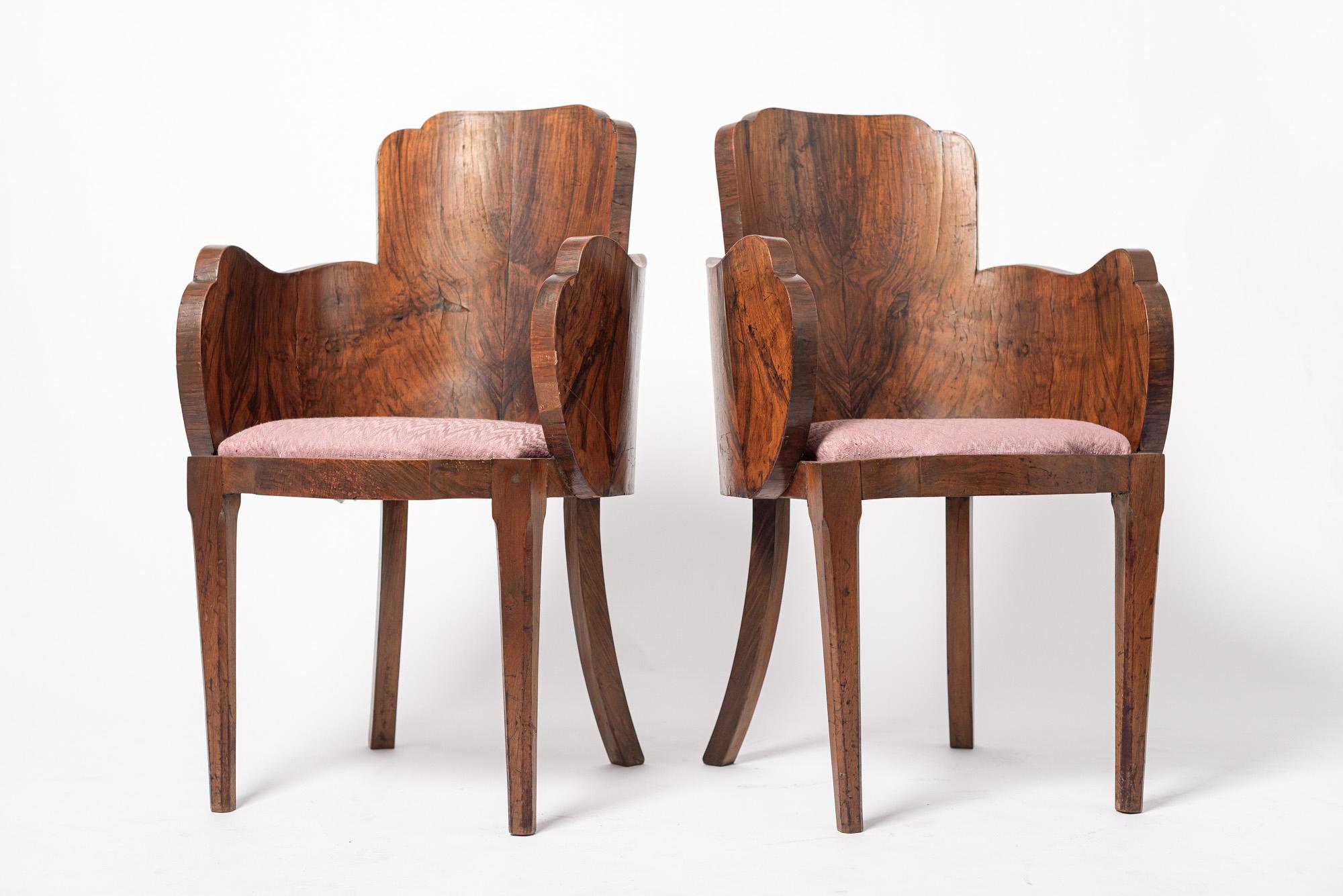 Cette paire exceptionnelle de chaises de salle à manger ou de salon Art déco vers 1930 présente un design unique et élégant avec un dossier arrondi en forme de tonneau et des accoudoirs avec un bord incurvé et festonné distinctif. Fabriquées à la