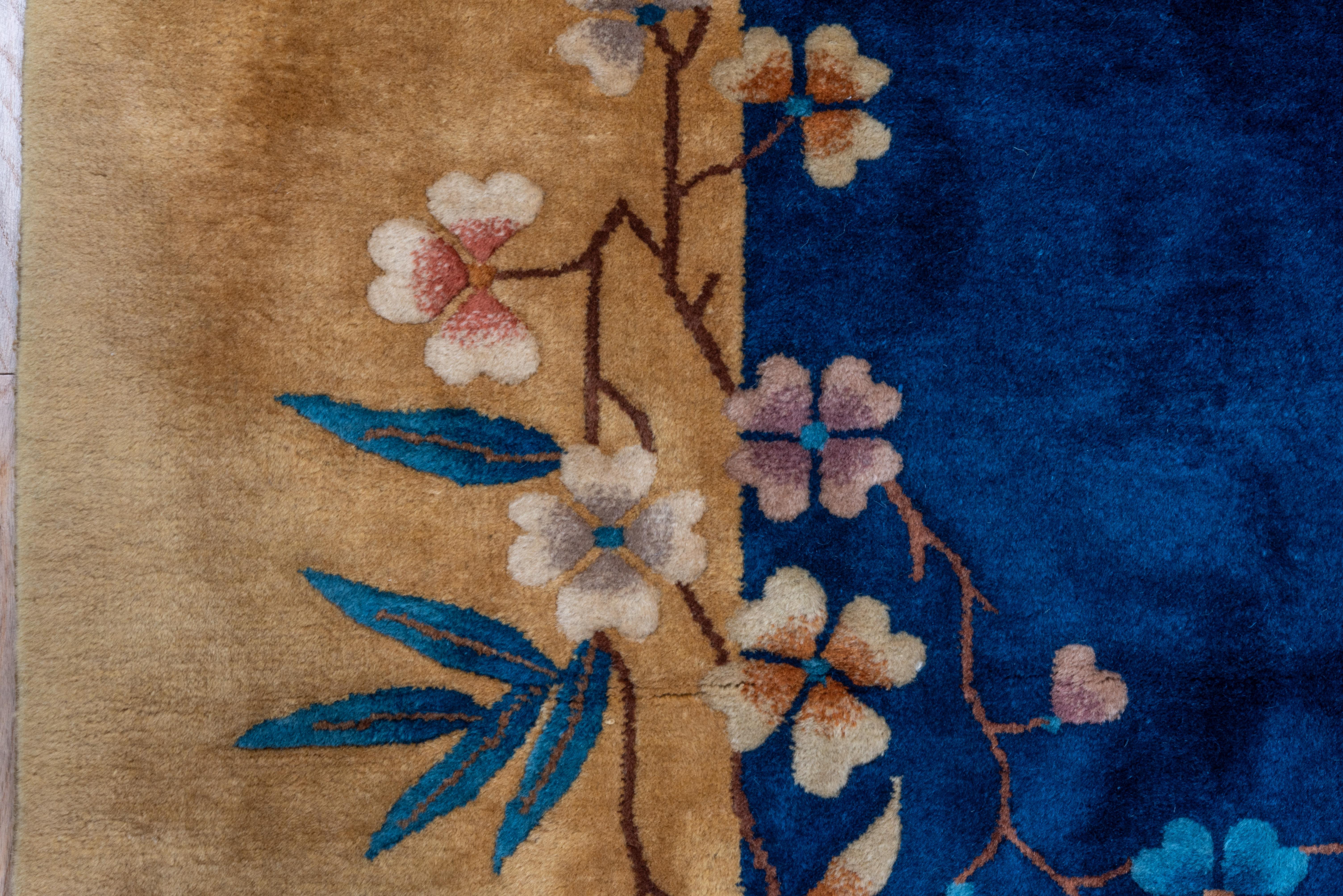 Here is one in an uncommon size, with an asymmetric pattern of floral sprays tying together the dark blue field with the straw border. Each stem shows mixed, different blossoms and leaves, including bamboos in one corner. Many flowers are shaded.