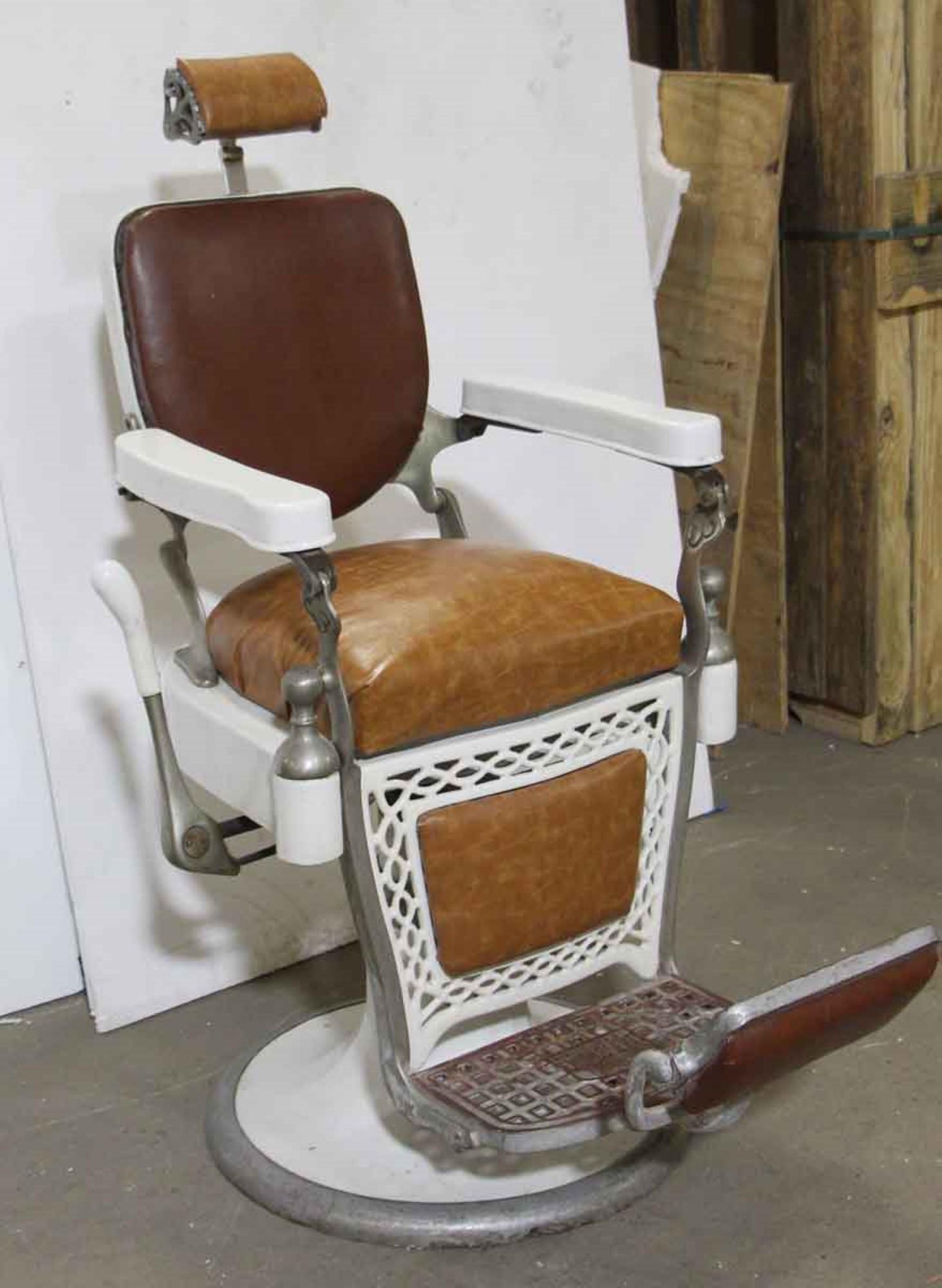 1930s brown and white barber chair with leather and vinyl upholstery, original porcelain and a spring cushion headrest. It is in excellent working condition. Made by Emil J. Paidar Co. Some of the original leather upholstery has been replaced with