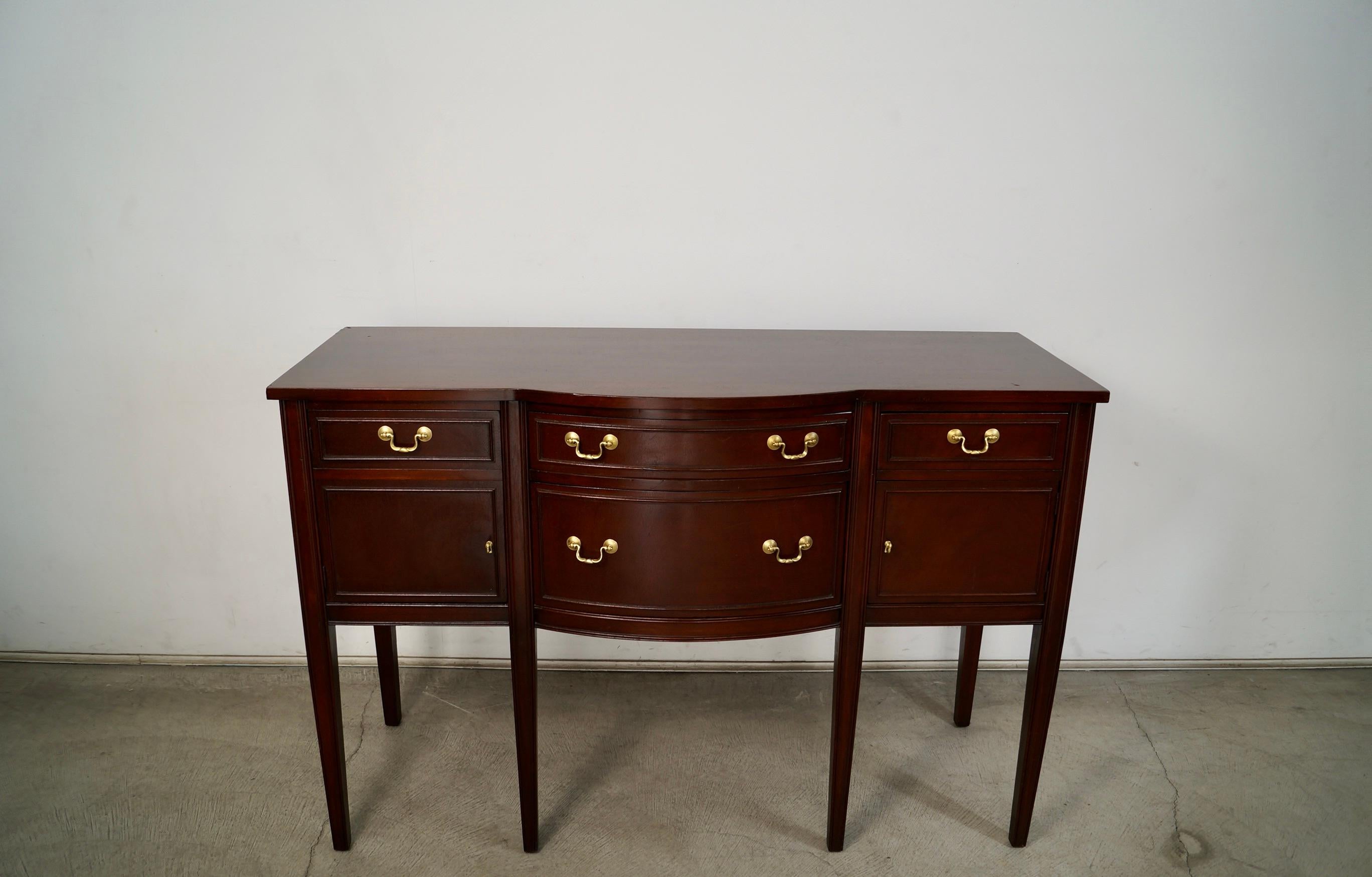 Antique 1930's credenza for sale. Made of mahogany in a mahogany finish, and has the original solid brass hardware. It's very solidly constructed, and in great vintage condition with some vintage wear. The left side has a cabinet door, and the