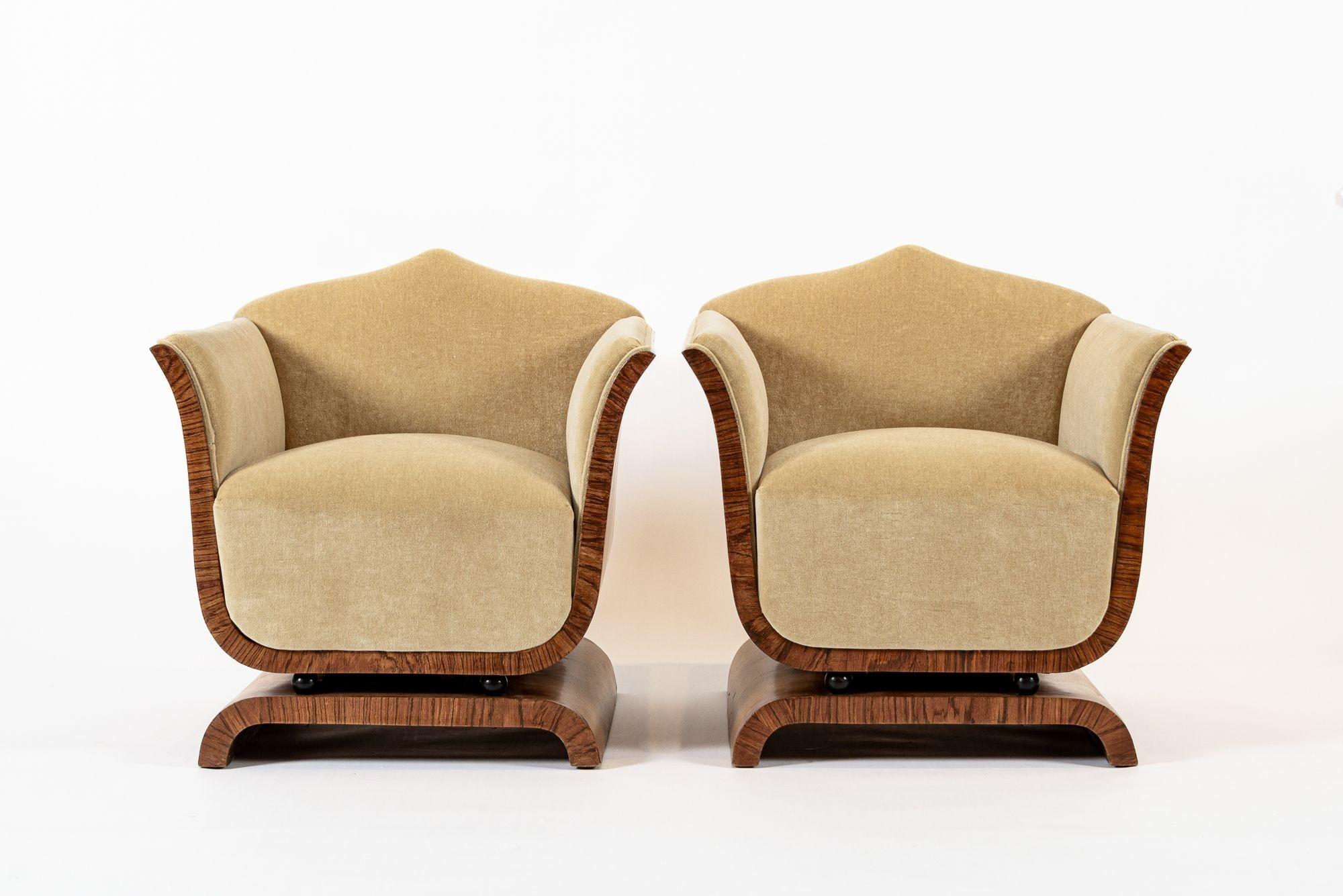 This stunning pair of French Art Deco lounge chairs circa 1930 feature a distinctively elegant design and unique proportion with a boxy shape and graceful, gentle curves. Incredibly well-crafted from solid wood with beautiful, rich burl wood French